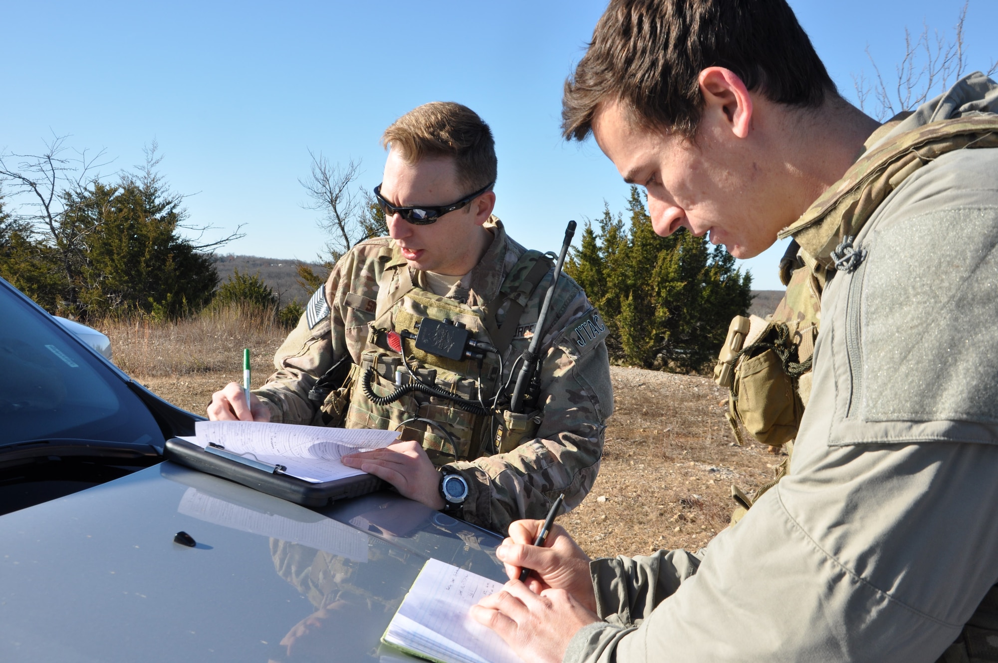 Instructor Staff Sgt. Steven Smith helps Senior Airman Phil Schneider, a student Joint Terminal Attack Controller, prepare coordinates to call in a simulated air strike during the class’s field training exercise south of Warsaw, Missouri on November 19. Academic portions of the class rely on JTACs playing the role of pilots in hypothetical missions, but the exercise gives students the opportunity to speak with experienced pilots from the 442d Fighter Wing over the radio in realistic scenarios. Warsaw has hosted the exercises since 1993. (U.S. Air Force photo/ Technical Sgt. Emily F. Alley)