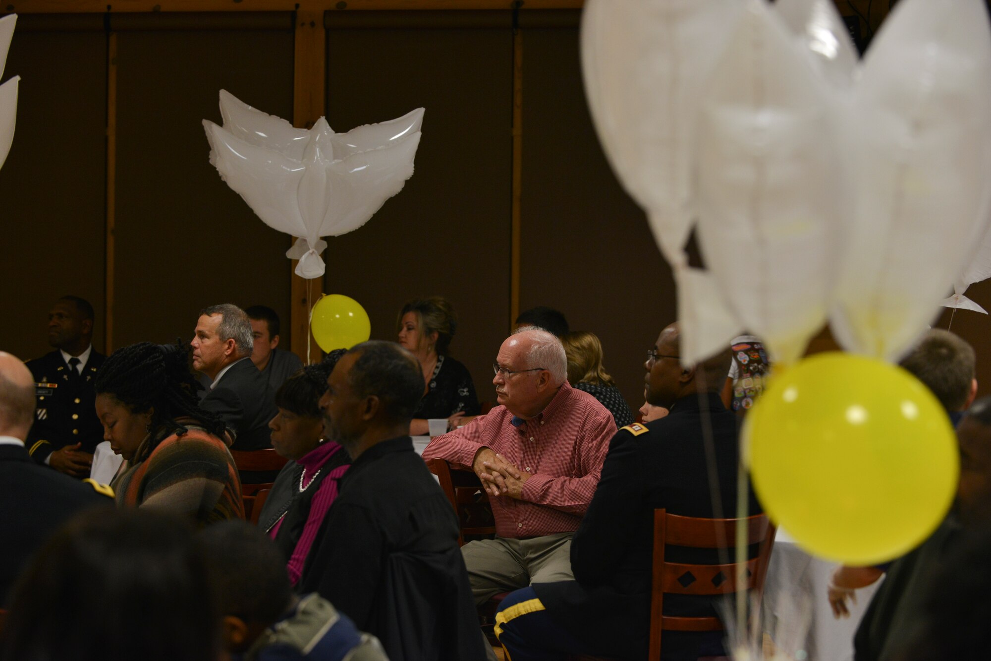 Richard Reynal (center, red shirt), a Gold Star family member, listens as U .S.  Army Maj. Gen. Robert M. Dyess, the deputy director of U.S. Army Capabilities Integration Center, speaks at the 5th Annual Survivor Outreach Services’ Thanks for Giving social at Fort Eustis, Va., Nov. 19, 2015. Reynal, his wife and their grandchildren attend Gold Star events to help cope with the passing of their daughter, Sgt. Caryn Nouv. (U.S. Air Force photo by Staff Sgt. Natasha Stannard)