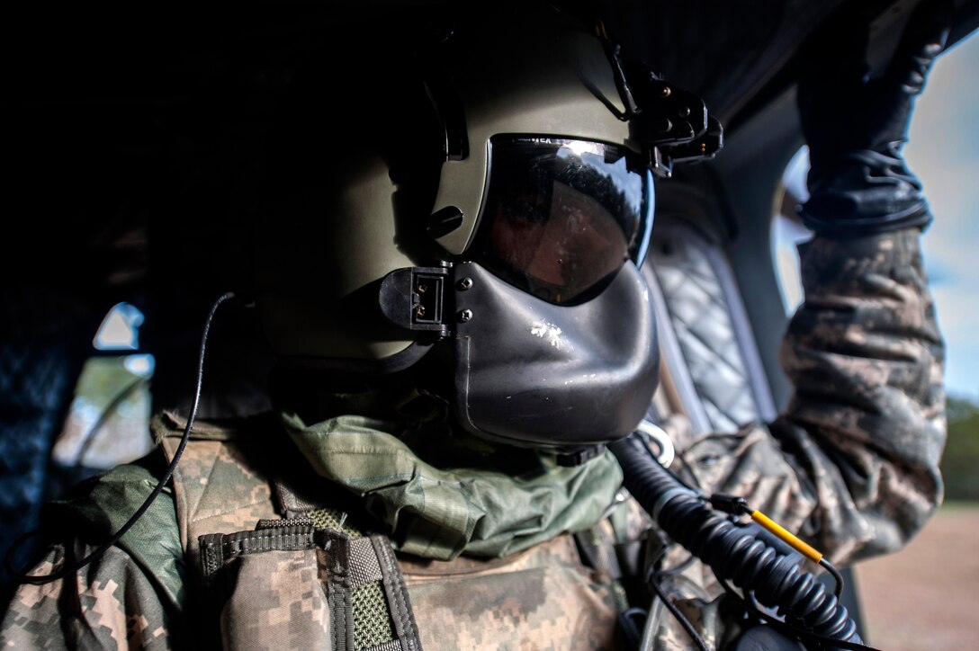 U.S. Army Cpl. Terrence Patterson, a crew member assigned to B Company, 5th Battalion (General Support) Aviation, 159th Aviation Regiment, looks out the crew door of a CH-47 Chinook during a training mission at Felker Army Air Field, Fort Eustis, Va., Nov. 18, 2015. The training mission tested the Joint Survival Air Mask rotary wing variant next generation gas mask, which is designed to make Mission-Oriented Protective Posture Level 4 convenient, but effective. With the new gas mask, Soldiers only have to place the removable face plate on in the event of a chemical, biological or radiological threat. (U.S. Air Force photo by Senior Airman Breonna Veal)  