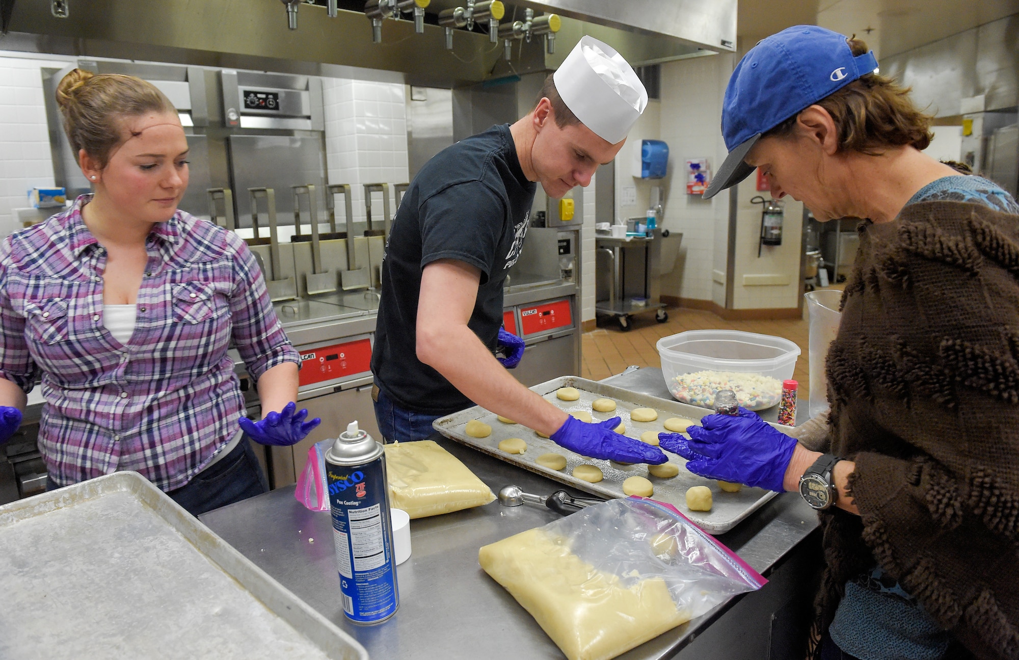 Volunteers bake thousands of cookies utilizing the Wolf's Den dining facility kitchen on Joint Base Elmendorf-Richardson, Alaska, Nov. 17, 2015. During the cookie drive volunteers collected dough, baked, sorted and packaged the cookies. The cookies will later be delivered to single Airmen and Soldiers living in the dorms and barracks to provide them with a homemade treat during the holiday season. (U.S. Air Force photo/Alejandro Peña)