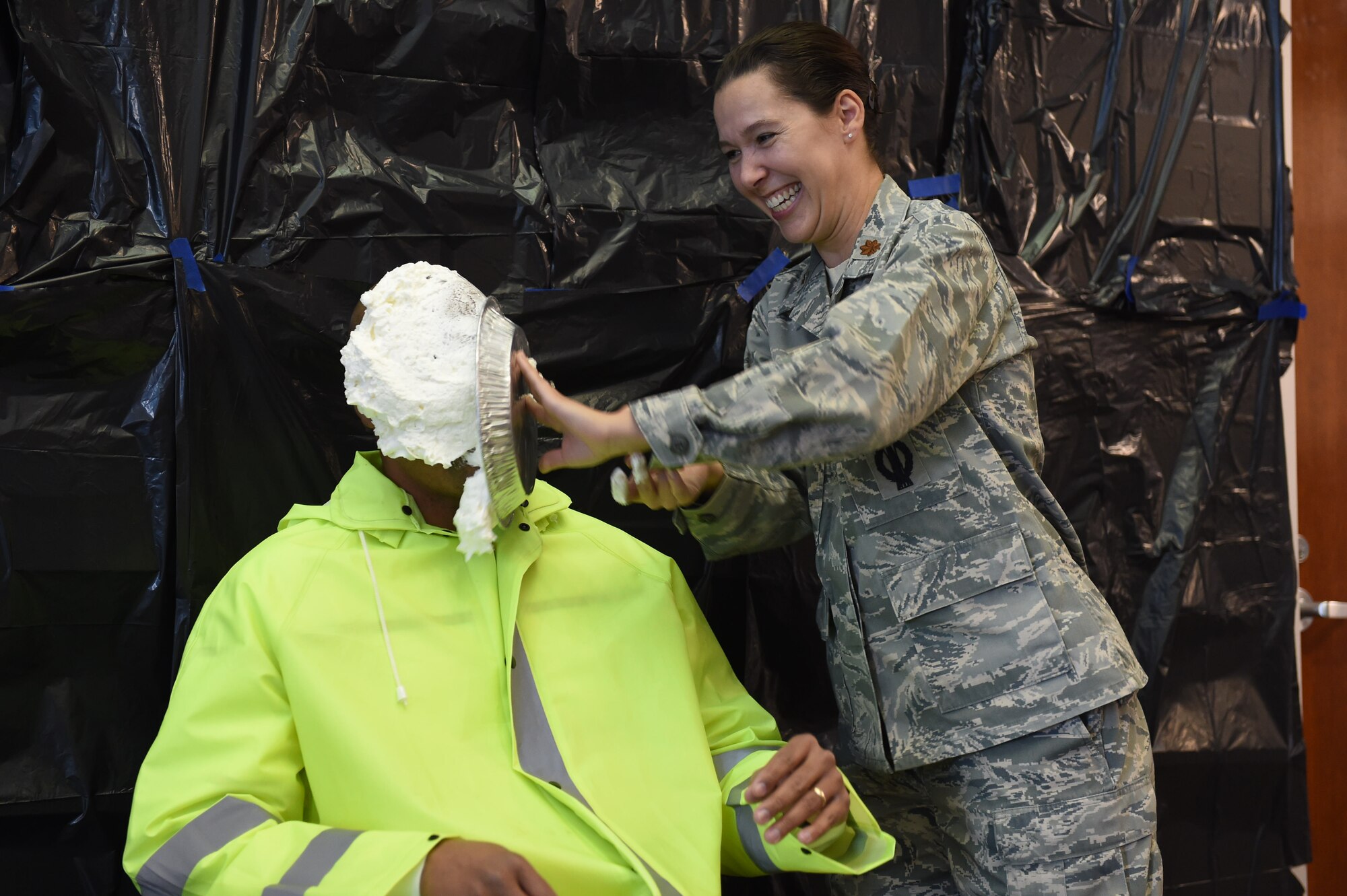 Gregory Walker, 460th Space Wing occupational safety manager, takes a pie in the face from Maj. April Reveteriano, 460th Space Wing Individual Mobilization Augmentee to the chief of safety, as a fundraiser for the Combined Federal Campaign Nov. 20, 2015, on Buckley Air Force Base, Colo. Buckley AFB held Wingman Day in order to recognize the men and women who continue the mission of the 460th Space Wing each and every day. (U.S. Air Force photo by Airman 1st Class Luke W. Nowakowski/Released)