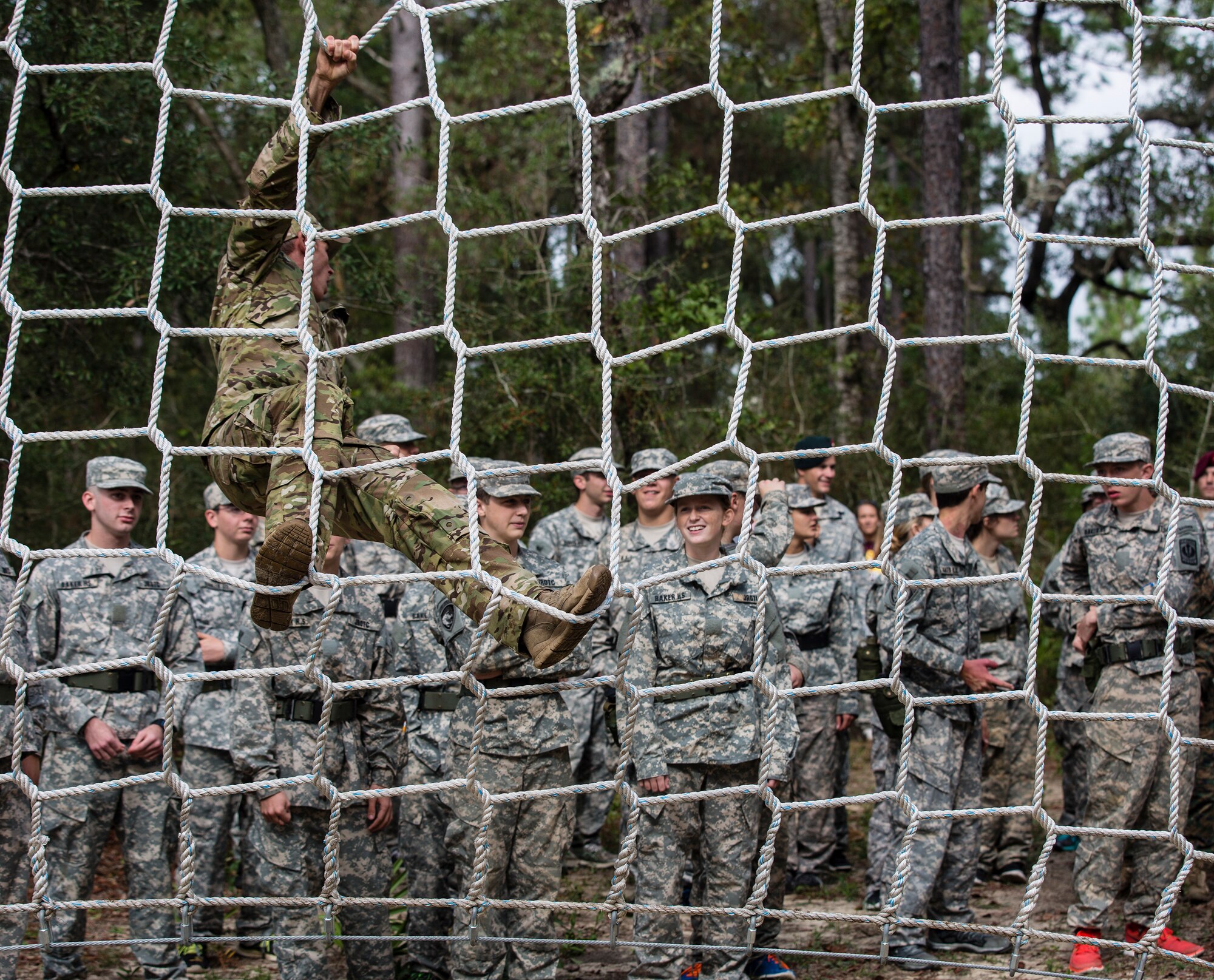 A Green Beret assigned to the 7th Special Forces Group (Airborne) demonstrates how to safely climb a cargo net obstacle to Army Junior Officer Reserve Training Corps Cadets Nov. 10. The Army JROTC cadets from Baker School in Northwest Florida trained with Special Forces soldiers from the group to prepare for an upcoming competition testing their physical and mental endurance.  (U.S. Army photo/Private 1st Class David Stewart)