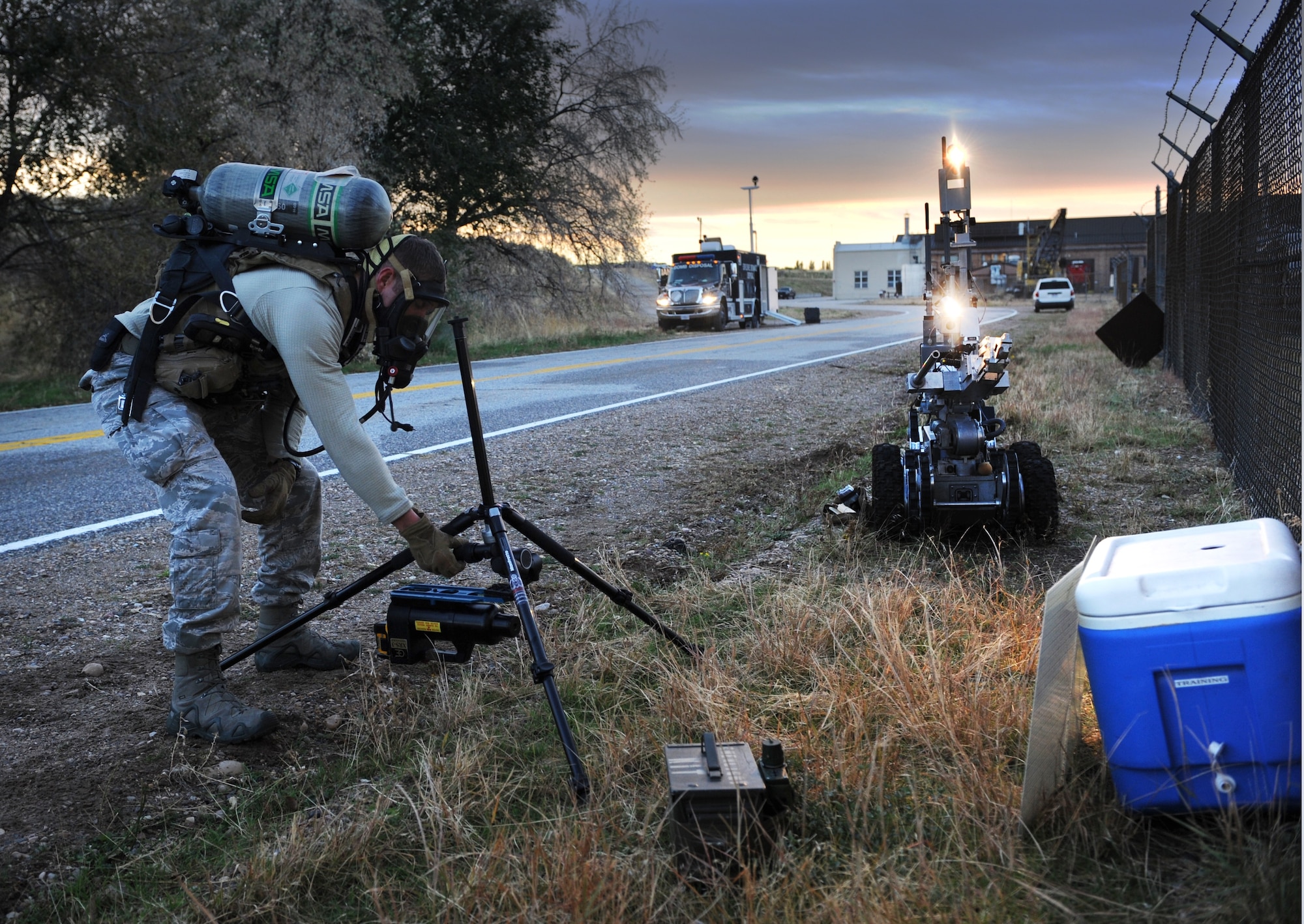 With the aid of lights and cameras on a remote-controlled robot, Senior Airman Garret Corbett, an Explosive Ordnance Disposal technician with the 775th EOD Flight at Hill Air Force Base sets up a mobile X-ray to examine the contents of a cooler during a training scenario on investigating suspicious packages. Once Corbett takes the X-ray, he can process them in a mobile computer lab in the command truck.  (U.S. Air Force photo/Micah Garbarino)