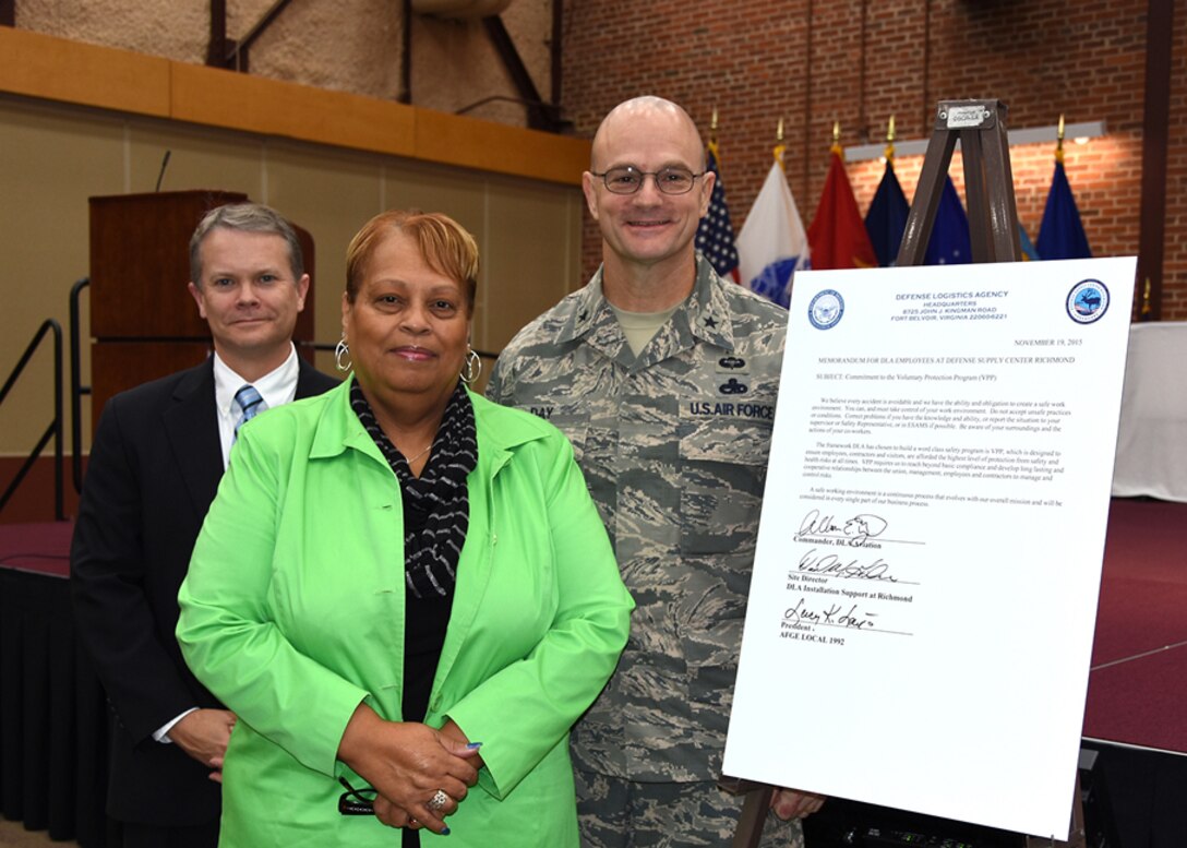 David Gibson, site director, DLA Installation Support at Richmond, Lucy Lewis, president, American Federation of Government Employees (AFGE) Local 1992, and DLA Aviation Commander Air Force Brig. Gen. Allan Day pose for a picture after signing the Voluntary Protection Program (VPP) commitment letter during the DSCR, Virginia, Safety Stand Down Day program at the Lotts Conference Center, Nov. 19, 2015. 