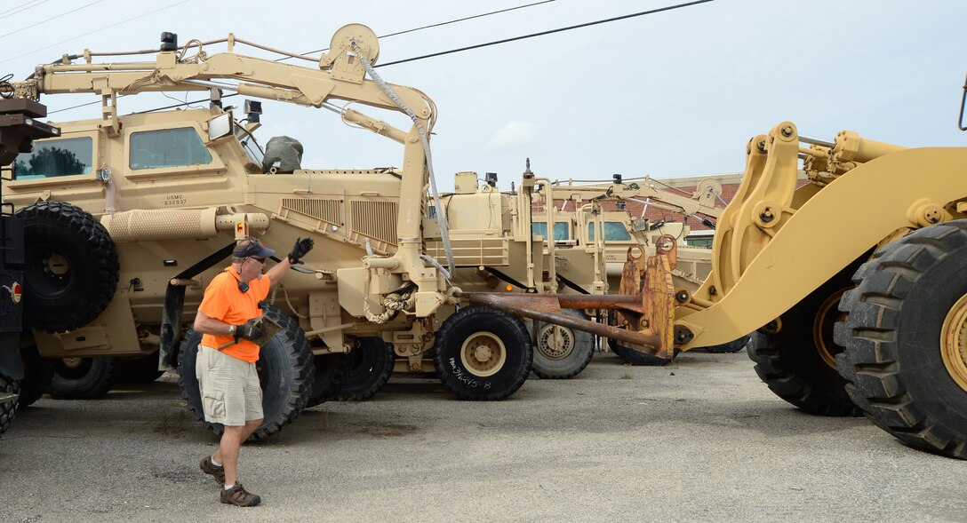 Donald Middlebrooks, engineering equipment operator, PrimeTech International, assists a driver during the transport of a mine-resistant ambush protected vehicle aboard Marine Corps Logistics Base Albany. The vehicle was delivered to an incoming equipment lot recently to be rebuilt.