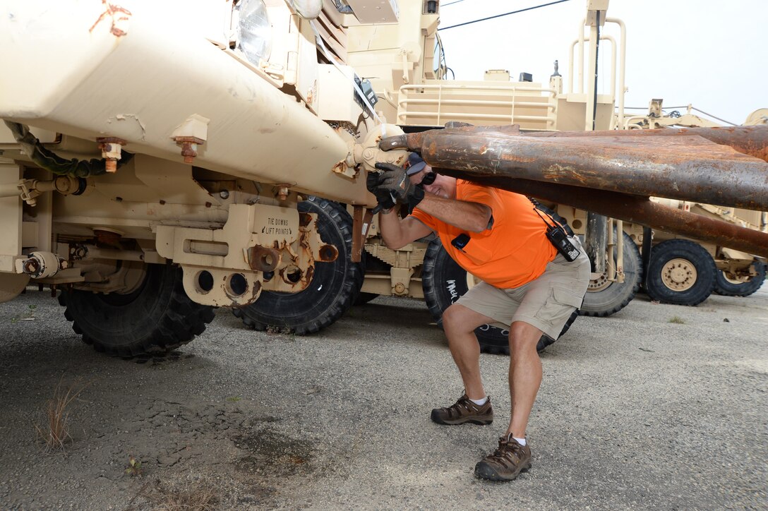 Donald Middlebrooks, engineering equipment operator, PrimeTech International, checks to ensure a mine-resistant ambush protected vehicle is securely attached prior to transport. The vehicle was delivered to an incoming equipment lot recently to be rebuilt.