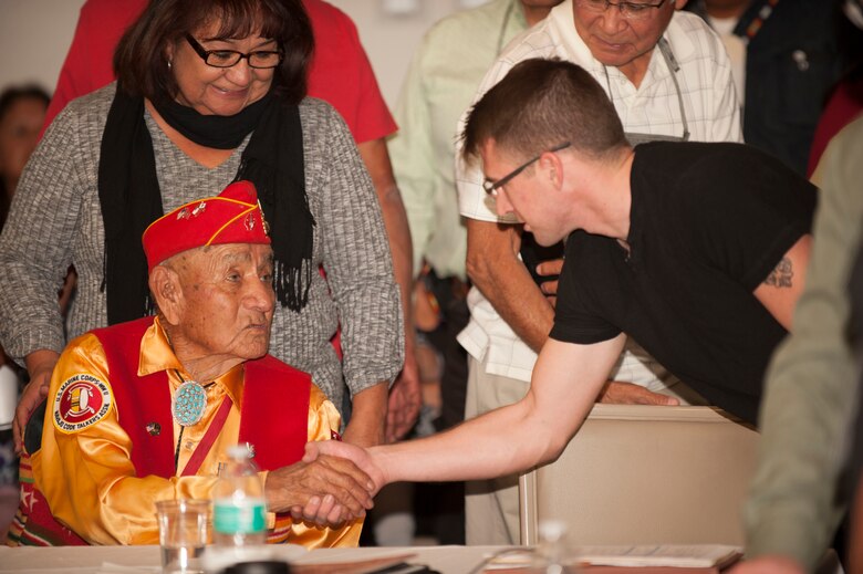Former U.S. Marine Corps Navajo Code Talker George Willie shakes hands with a grateful audience member during at the Native American Heritage Month Meeting at Nellis Air Force Base, Nev., Nov. 19, 2015. Willie was accompanied by his wife and two of his daughters who helped to tell the story of hi service in the Pacific theater during World War II. (U.S. Air Force photo by Senior Airman Joshua Kleinholz)