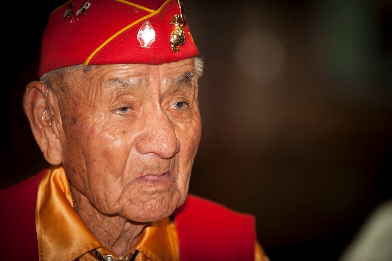 Former U.S. Marine Corps Navajo Code Talker George Willie looks on as his daughter tells his military story during the Native American Heritage Month Meeting at Nellis Air Force Base, Nev., Nov. 19, 2015. Willie enlisted in the Marine Corps shortly after the attack on Pearl Harbor in 1941 and went on to serve in a number of key battles, including the invasion of Okinawa in 1945. Navajo code talkers were recruited in order to ensure communications security against the Japanese, who had become adept at cracking U.S. codes. (U.S. Air Force photo by Senior Airman Joshua Kleinholz)