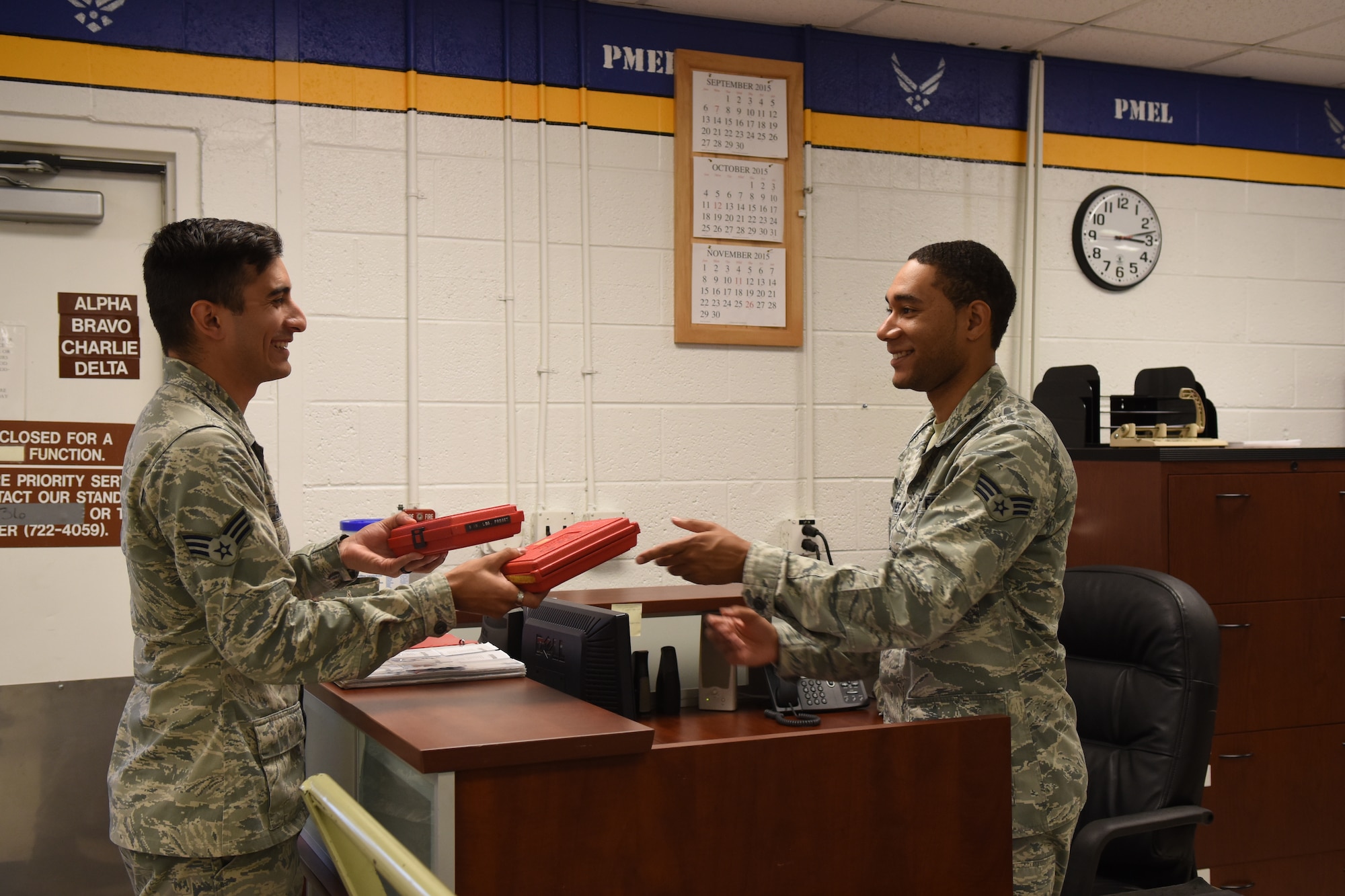 Senior Airman Emilio Blanco (left), 4th Component Maintenance Squadron avionics flight support team leader, receives equipment from Senior Airman Reggie Graves, 4th CMS precision measurement equipment lab production control technician, Nov. 18, 2015, at Seymour Johnson Air Force Base, North Carolina. The test, measurement and diagnostic equipment flight’s scheduling section handles all incoming and outgoing equipment the technicians in PMEL handle every day. (U.S. Air Force photo/Airman Shawna L. Keyes)