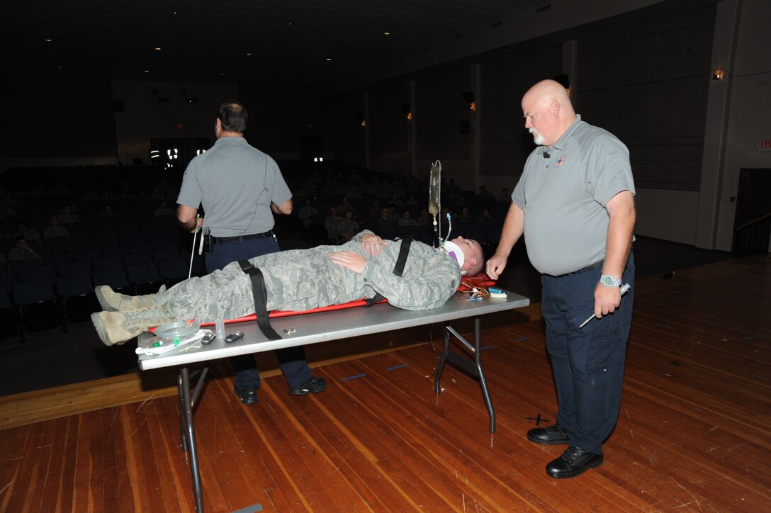 Greg McCarty, retired fire fighter and paramedic out of Miami, right, demonstrates proper victim response measures on Senior Airman Jordan Gaines, 22nd Communications Squadron cyber assurance technician, as Ralph Jimenez, retired fire fighter and paramedic out of Tampa, narrates to the audience, Nov. 18, 2015, at McConnell Air Force Base, Kan. Using their own personal experience from many years on the job, they discuss poorly made decisions such as: driving under the influence, not wearing seat belts, and texting and driving, and the possible consequences from these actions. (U.S. Air Force photo/Airman Jenna K. Caldwell)