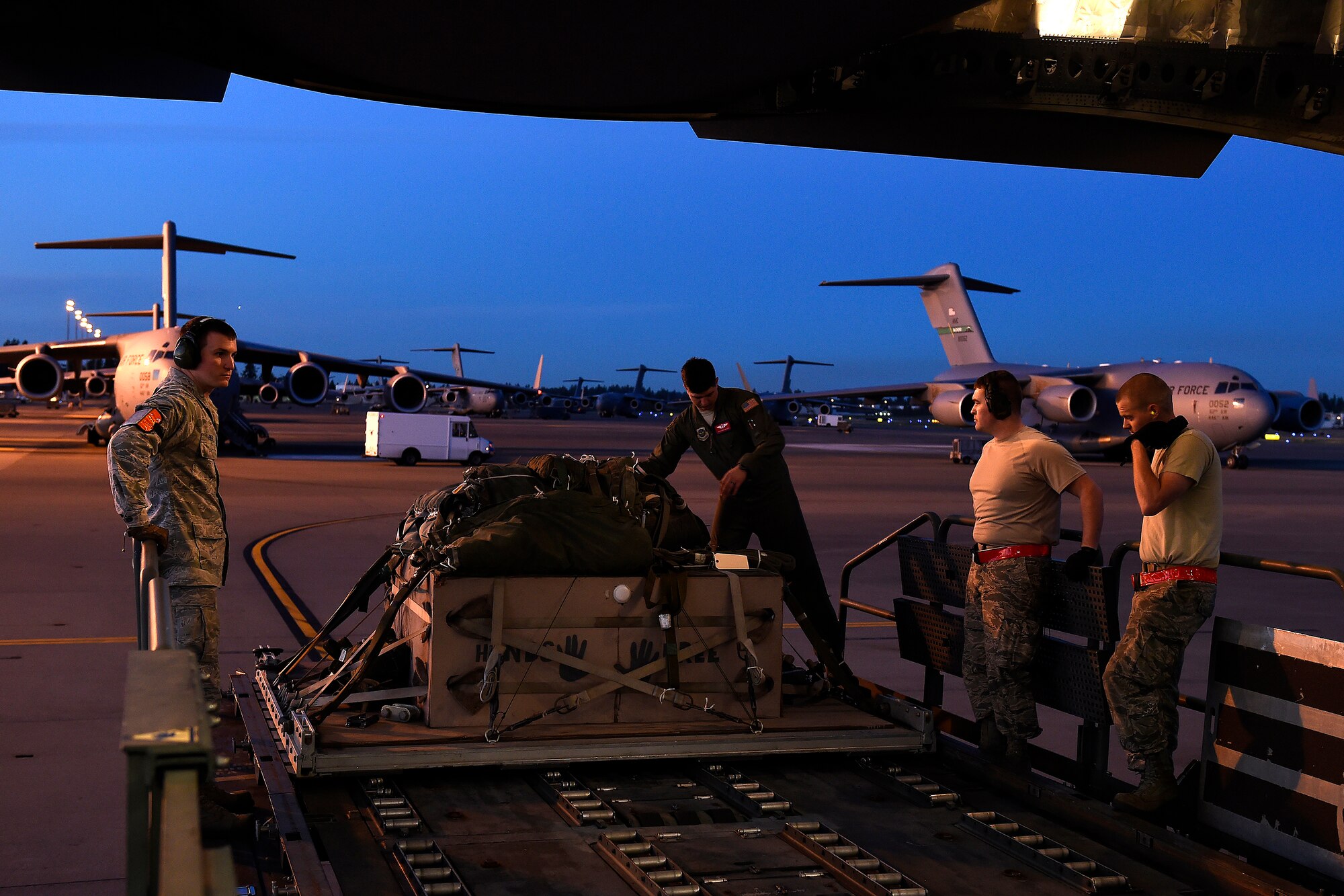 Staff Sgt. Eric Bailey (center), 62nd Operations Support Squadron joint airdrop inspector, assists with the loading of an air drop bundle Oct. 21, 2015, at Joint Base Lewis-McChord, Wash. Bailey must inspect the bundle after the loadmaster flying the mission loads and secures it. (U.S. Air Force photo by Staff Sgt. Tim Chacon)