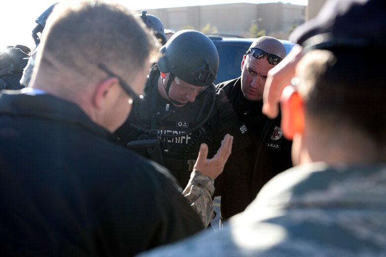 Base security forces and El Paso County law enforcement officials plan their coordinated response during a hostage exercise Thursday, Nov. 18, 2015, in the fitness center at Schriever Air Force Base, Colorado. The exercise tested and validated mutual aid agreements with El Paso County emergency response forces. (U.S. Air Force photo/Christopher DeWitt)