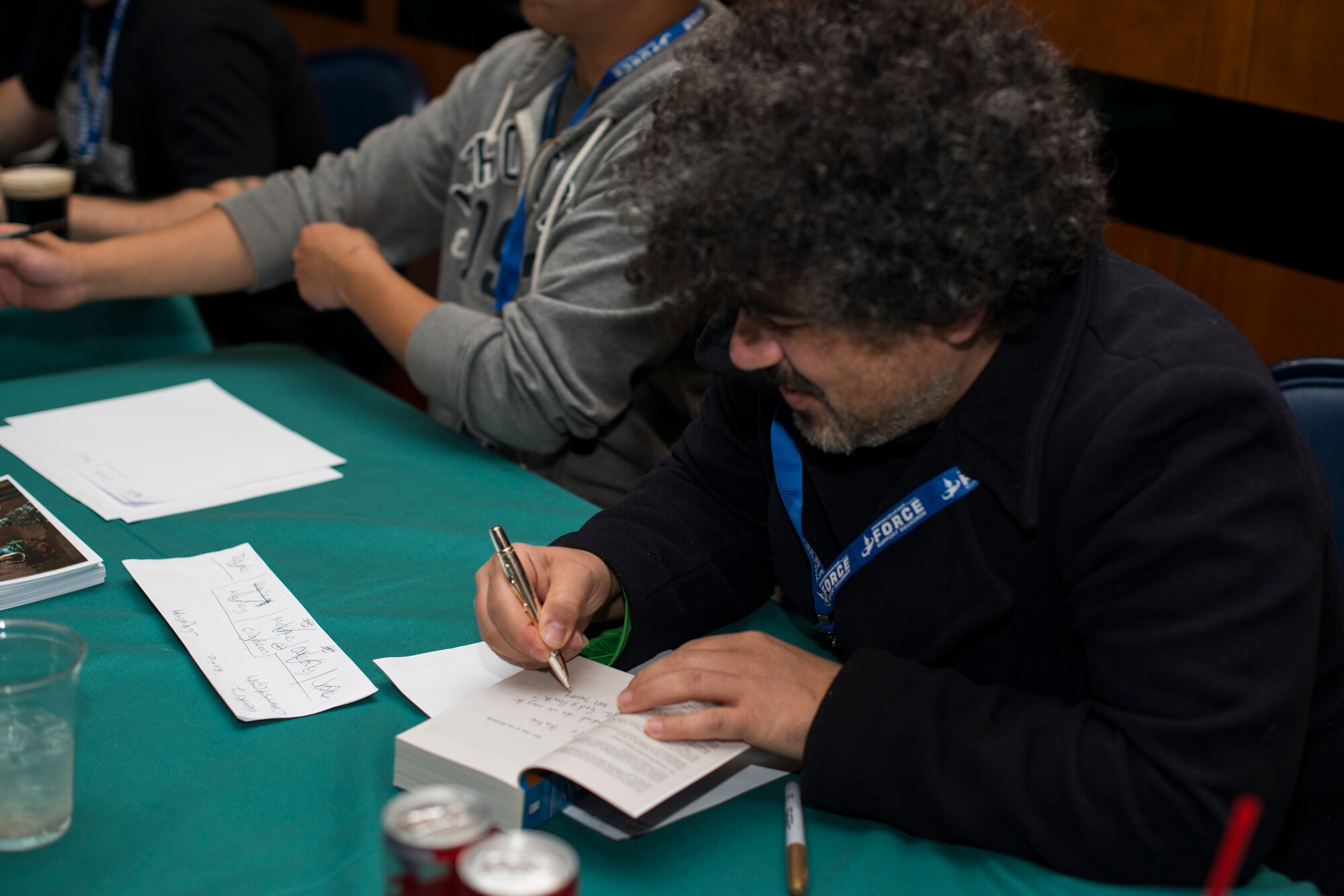 Miltos Yerolemou, film actor, autographs a Game of Thrones book during Operation Sci-Fi Con at Spangdahlem Air Base, Germany, Nov. 23, 2015. Yerolemou played Syrio Forel, sword master, in the TV adaptation of the book, Game of Thrones. (U.S. Air Force photo by Staff Sgt. Christopher Ruano/Released)
