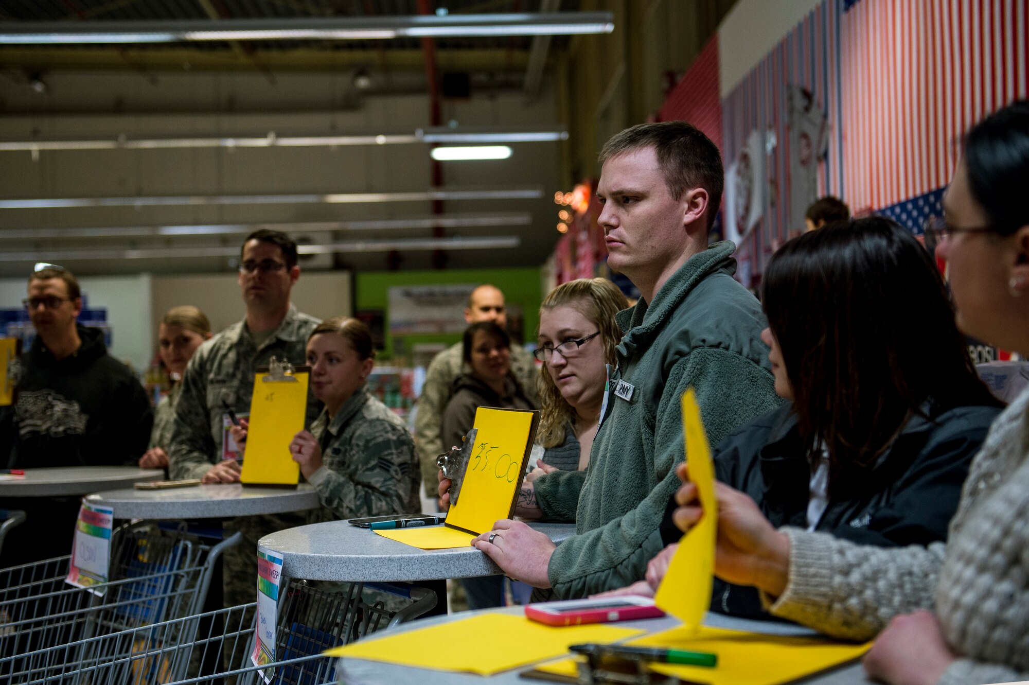 Event participants hold a piece paper with a price on it during the 2015 Commissary Sweep at Spangdahlem Air Base, Germany, Nov. 23, 2015. The event allowed the contestants to shop for groceries, solve riddles and have fun. (U.S. Air Force photo by Senior Airman Rusty Frank/Released)