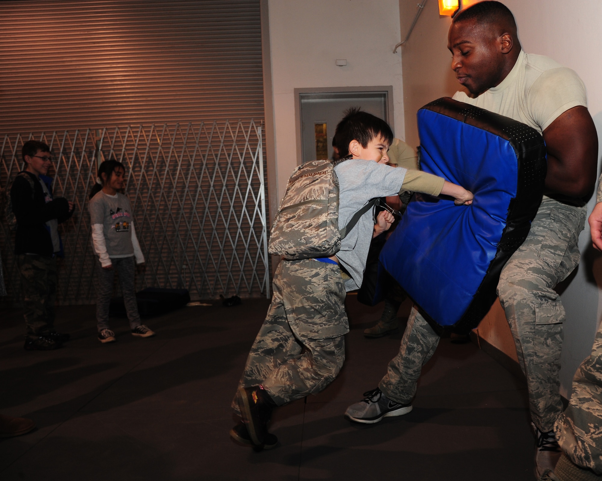 U.S. Air Force Senior Airman Vincell Shadricks, a 509th Security Forces Squadron member, teaches combatives to children during Operation Spirit at Whiteman Air Force Base, Mo., Nov. 21, 2015. The children learned how to take down and handcuff an attacker during a combat situation. (U.S. Air Force photo by Senior Airman Keenan Berry)