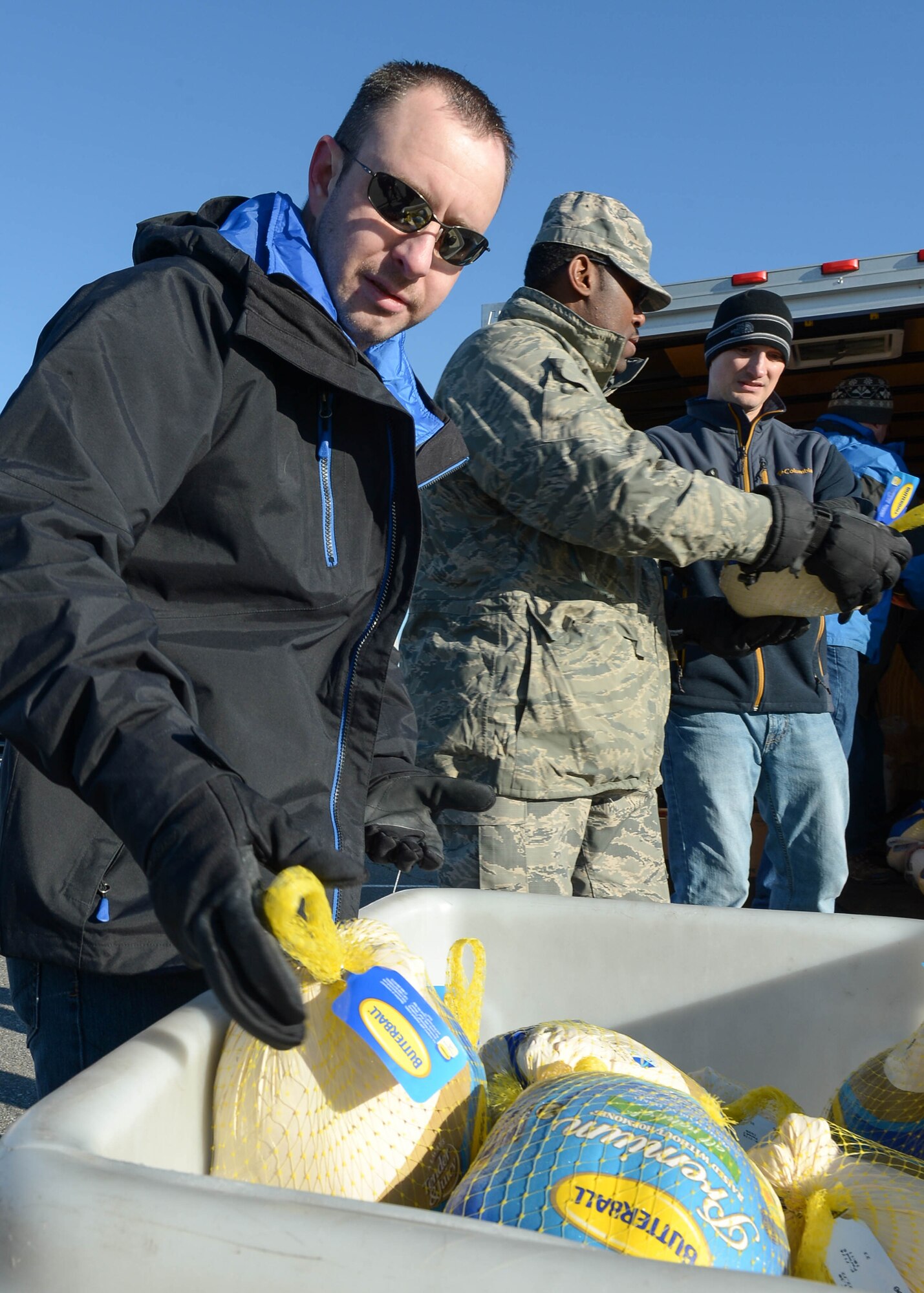 Master Sgt. Jason Oliver, left, Chief Master Sgt. Omar Hardman, center, and Master Sgt. John Fisher collect turkeys, hams and other traditional Thanksgiving meal items during a drive at the base Commissary Nov. 24. Hanscom senior NCOs collected the items to give to junior members of the workforce in need. (U.S. Air Force photo by Jerry Saslav)