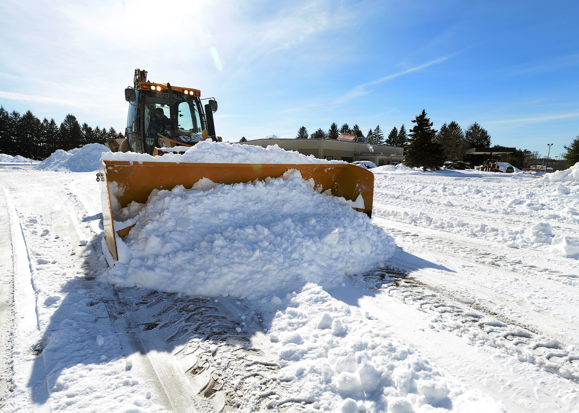 Members of the 66th Civil Engineering Division clear snow from a parking lot following a winter storm that hit the region last winter. When winter weather makes traveling a challenge, Hanscom personnel have a number of options available to find out if base operations are affected or delayed arrival is authorized. (U.S. Air Force photo by Jerry Saslav)
