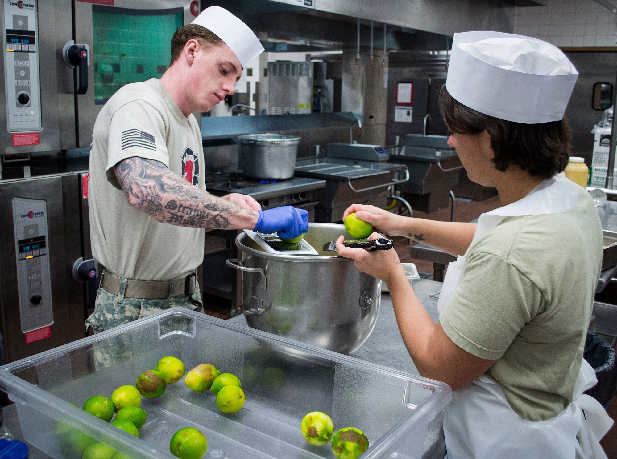 Culinary specialists assigned to the 7th Special Forces Group (Airborne) grate lime peels for a zest as they and others prepare a Thanksgiving meal in the unit’s dining facility November 23.  The group’s culinary specialist team prepared over 600 pounds of turkey, 115 pounds of steamship round and 184 pounds of ham for serving to the group’s soldiers, families and friends. (U.S. Army photo/Maj. Thomas Cieslak)