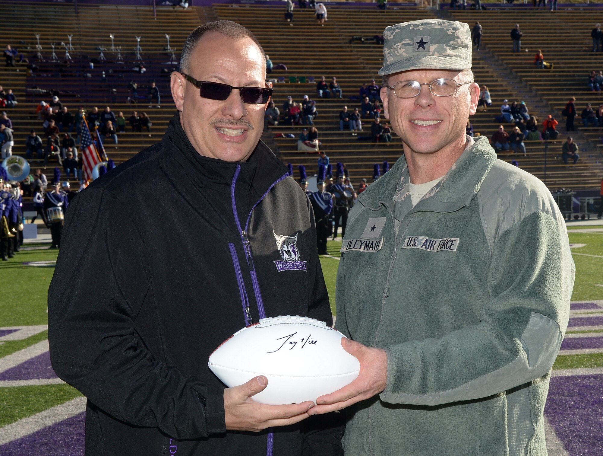 Weber State University Associate Athletics Director Ron Goch presents an autographed football to Ogden Air Logistics Complex Commander Brig. Gen. Steven J. Bleymaier before kickoff Nov. 21 at WSU’s Stewart Stadium, Ogden, Utah. The game was played in honor of military personnel, including those associated with Hill Air Force Base. WSU defeated Idaho State 35-14 in their last home game of the year. (U.S. Air Force photo/Alex R. Lloyd)