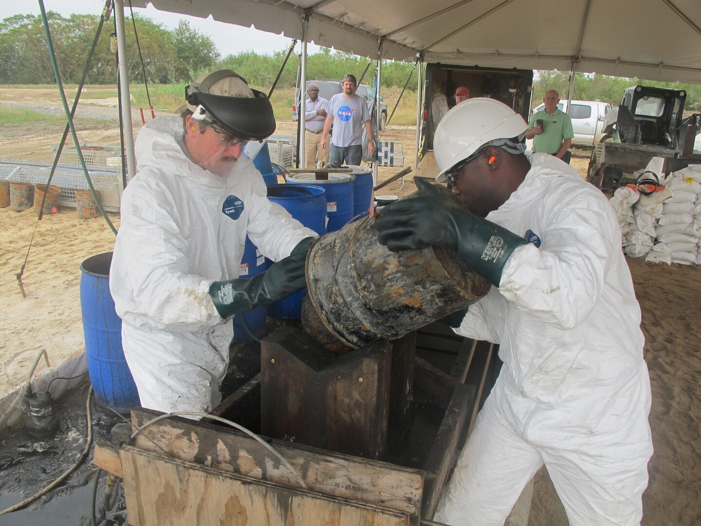 Workers flush munitions with hot water and MuniRem during inertion operations Nov. 4. Liquids carry black powder down a stepped trough system, which was built with 2-by-4s onsite. The stepped system is a means for collecting progressively finer black powder particulates, which are then scooped and further contained.
