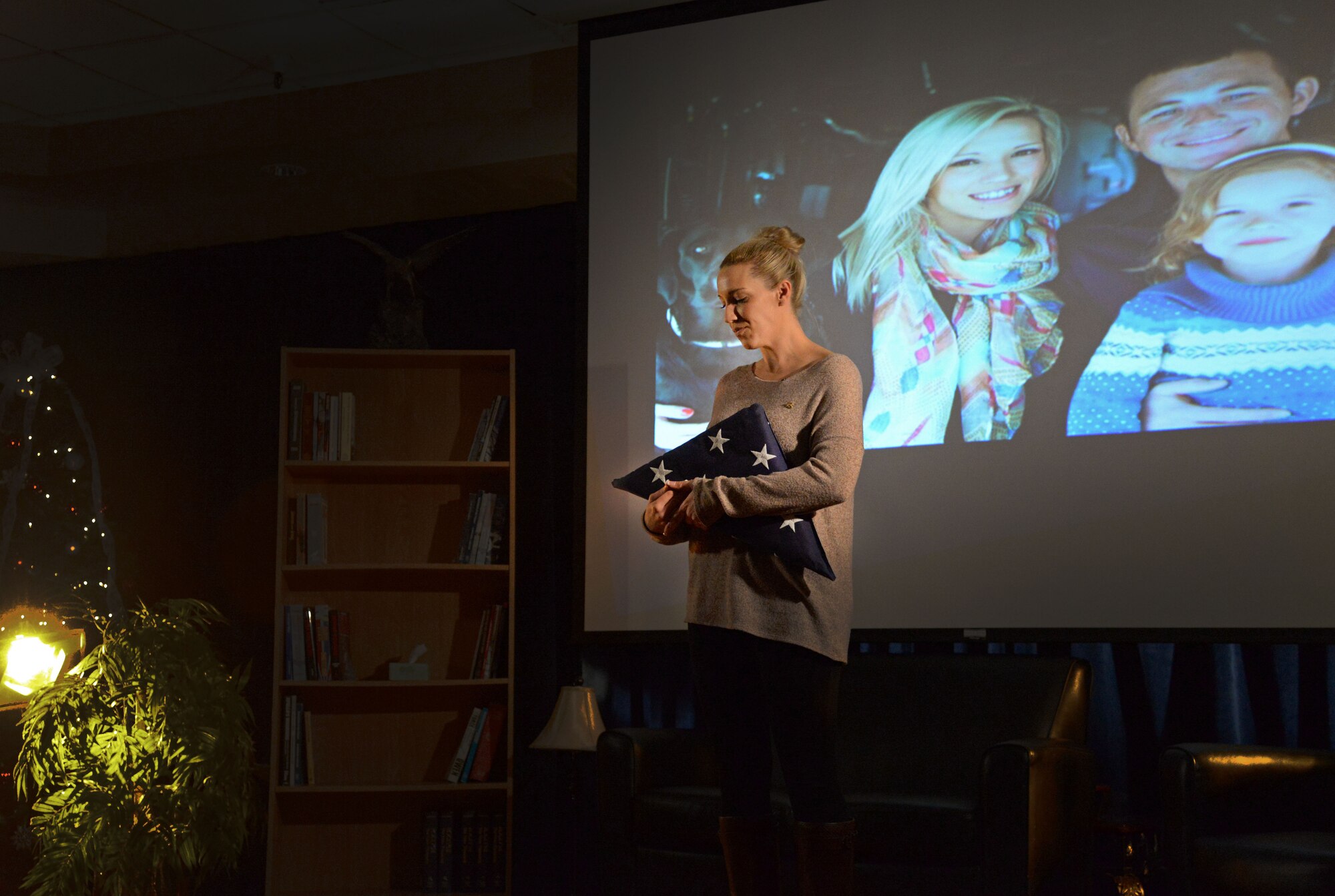 Samantha Lewis, widow of the late Staff Sgt. Jordan Lewis, tightly hugs a folded flag while sharing her story of loss during the second Storytellers Nov. 19, 2015, at Cannon Air Force Base, N.M. Lewis recounted Jordan’s passing, who tragically lost his life during a training accident at Melrose Air Force Range May 11, 2015. (U.S. Air Force photo/Staff Sgt. Alexx Pons) 