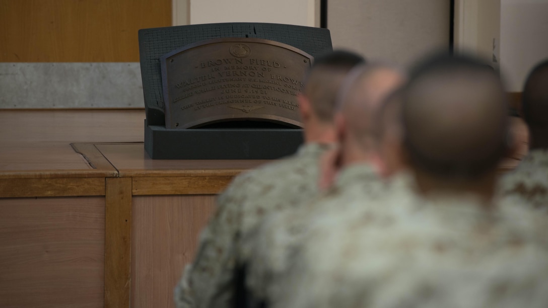 A plaque dedicated to 2nd Lt. Walter V. Brown sits in front of candidates of Officer Candidate School learning about Marine officer history at Marine Corps Base Quantico, Virginia, Nov. 20, 2015. Brown, a former squadron commander, was killed in a crash during an exercise at Quantico,  on June 9, 1921. (U.S. Marine Corps photo by Sgt. Eric Keenan)