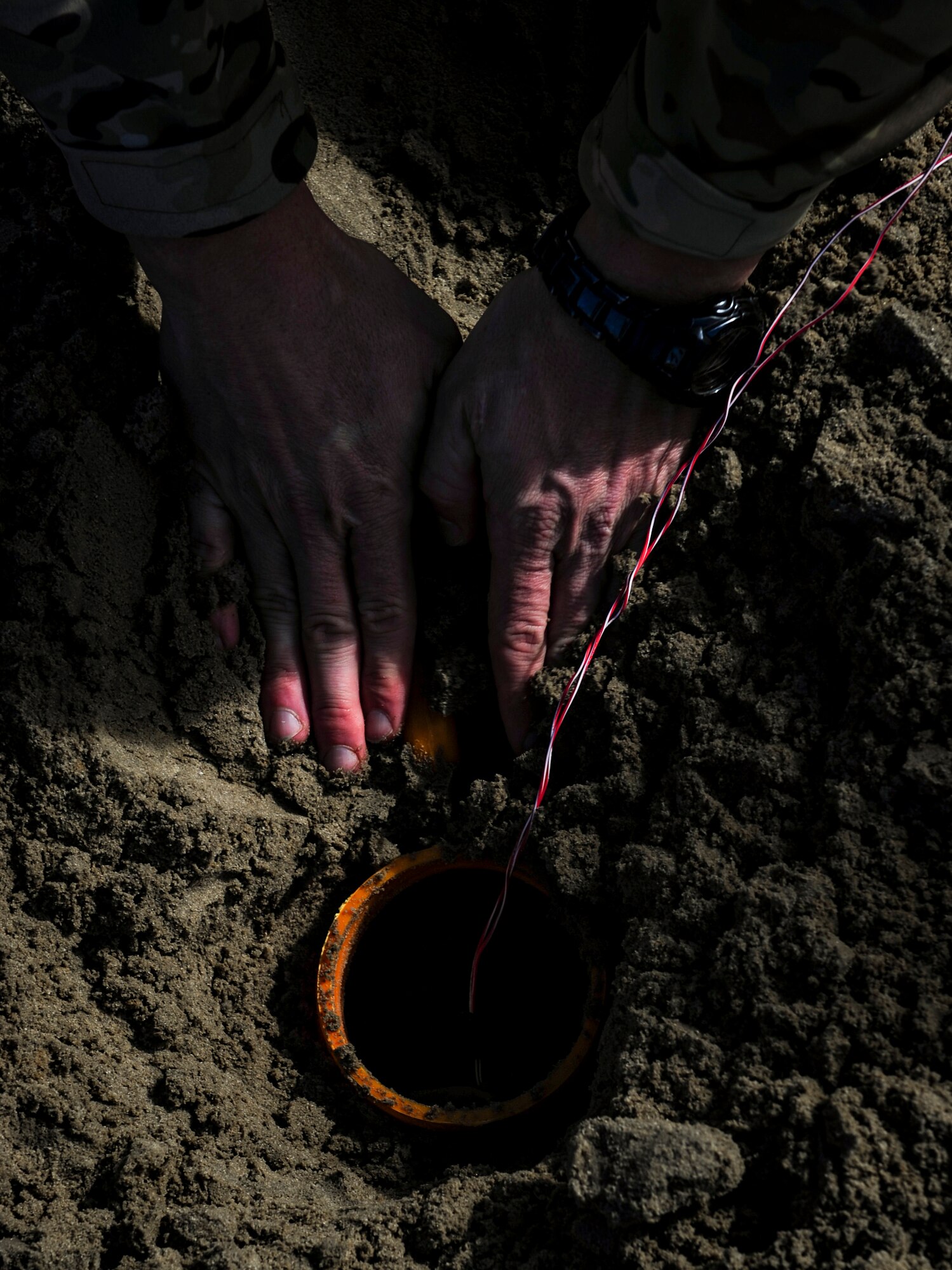 Master Sgt. Ronnie Brickey, an explosive ordnance disposal operations section chief with the 1st Special Operations Civil Engineer Squadron, packs dirt around an improvised explosive device at Hurlburt Field, Fla., Nov. 19, 2015. Wood boxes, plastic containers and backpacks are some items that can be used to make an improvised explosive device, as well as multiple types of batteries. (U.S. Air Force photo by Senior Airman Meagan Schutter)