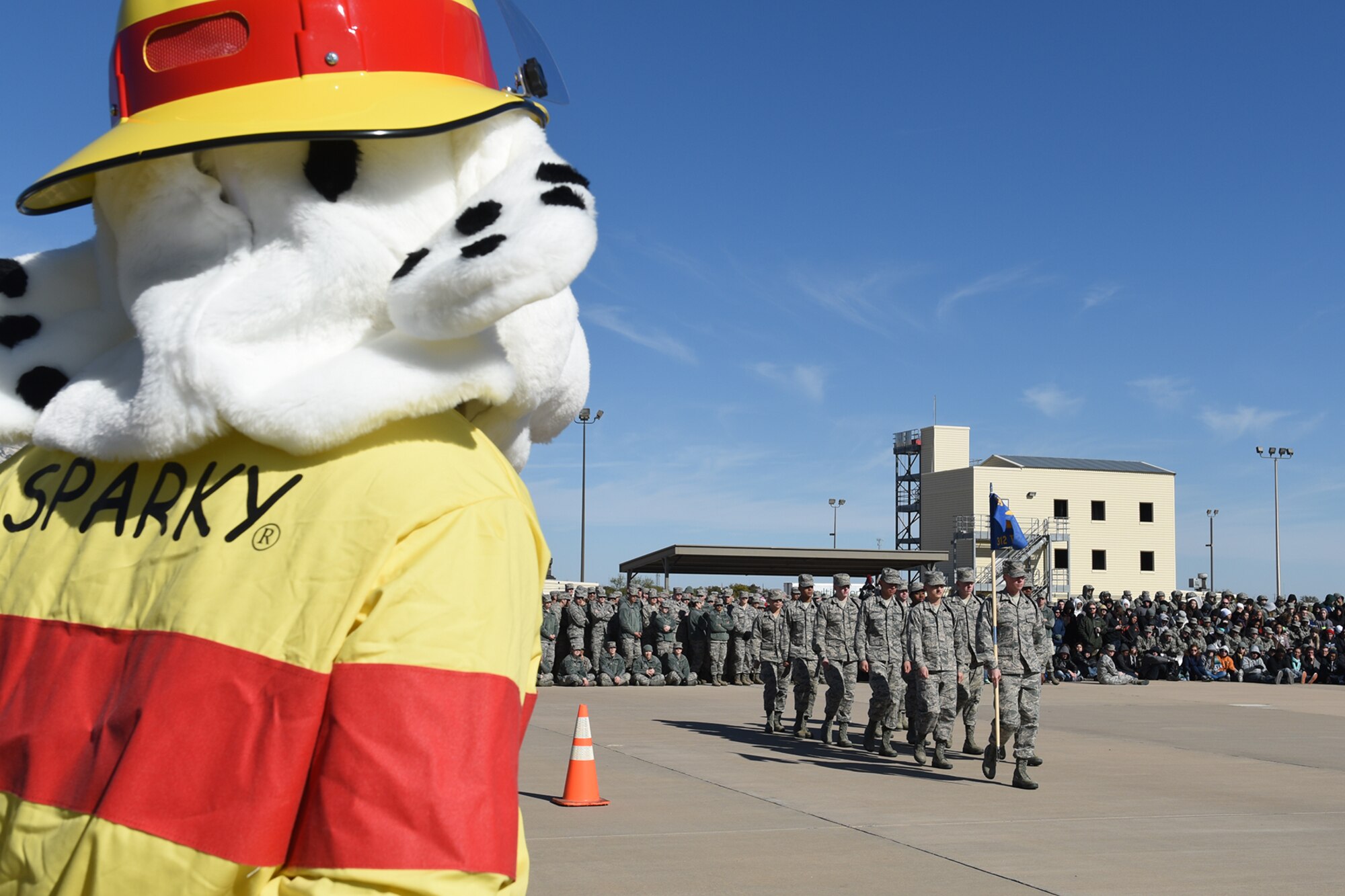 Sparky, 312th Training Squadron mascot, watches the 312th TRS black rope drill team perform a regulation drill during a 17th Training Group drill competition for the 7th Annual Goodfellow Community Appreciation Day at the fire training pad on Goodfellow Air Force Base, Texas, Nov. 21, 2015. The drill competition featured three teams competing against each other in open ranks, exhibition drill and regulation drill. (U.S. Air Force photo by Staff Sgt. Laura R. McFarlane/Released)