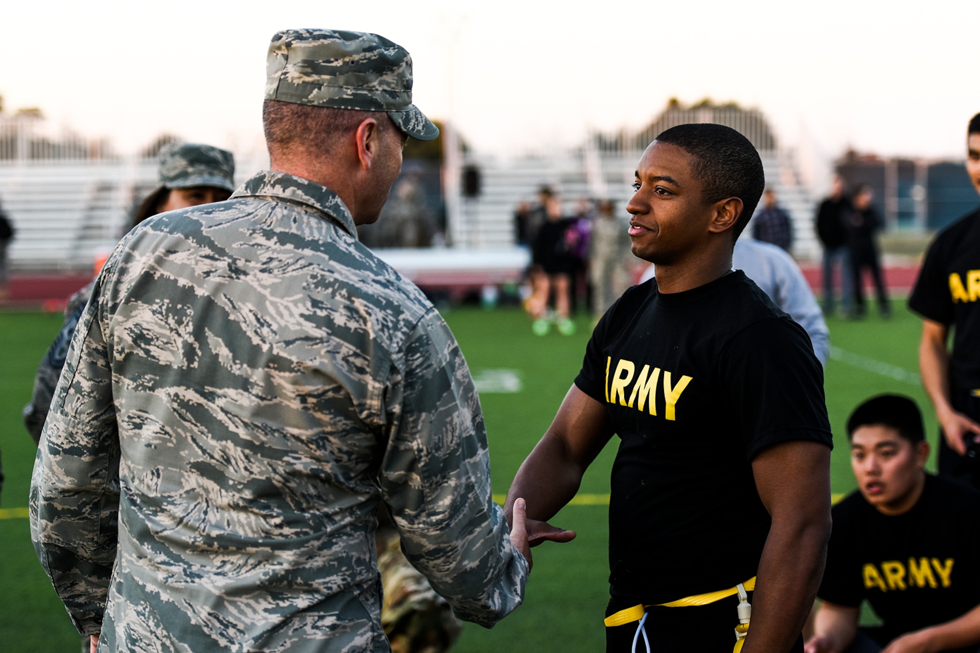 U.S. Air Force Col. Michael L. Downs, 17th Training Wing Commander, congratulates and presents U.S. Army Spc. Gerardo Aponte, 344th Military Intelligence Battalion student, with a coin after winning the annual Army and Navy football game on Goodfellow Air Force Base, Texas, Nov. 24, 2015. (U.S. Air Force Photo by Airman 1st Class Devin Boyer/Released)
