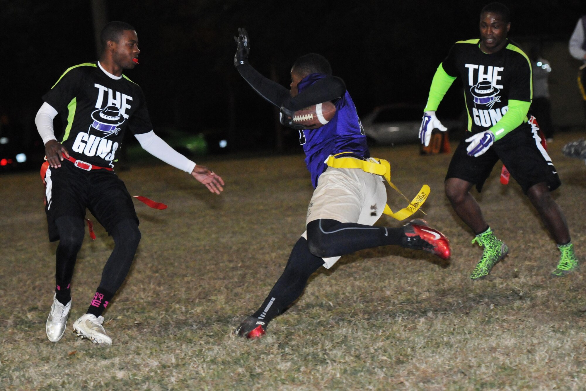 Seaman Dejhaun Monroe, Naval Mobile Construction Battalion 133rd equipment operator, and Petty Officer 2nd Class Xavier Knowlesball, NMCB 133rd builder, surround Senior Airman Aaron Calhoun, 403rd Maintenance Squadron hydraulics mechanic, as he runs the ball during the intramural flag football championship game Nov. 23, 2015, Keesler Air Force Base, Miss. The 403rd Wing defeated NMCB, 30-18. (U.S. Air Force photo by Kemberly Groue)