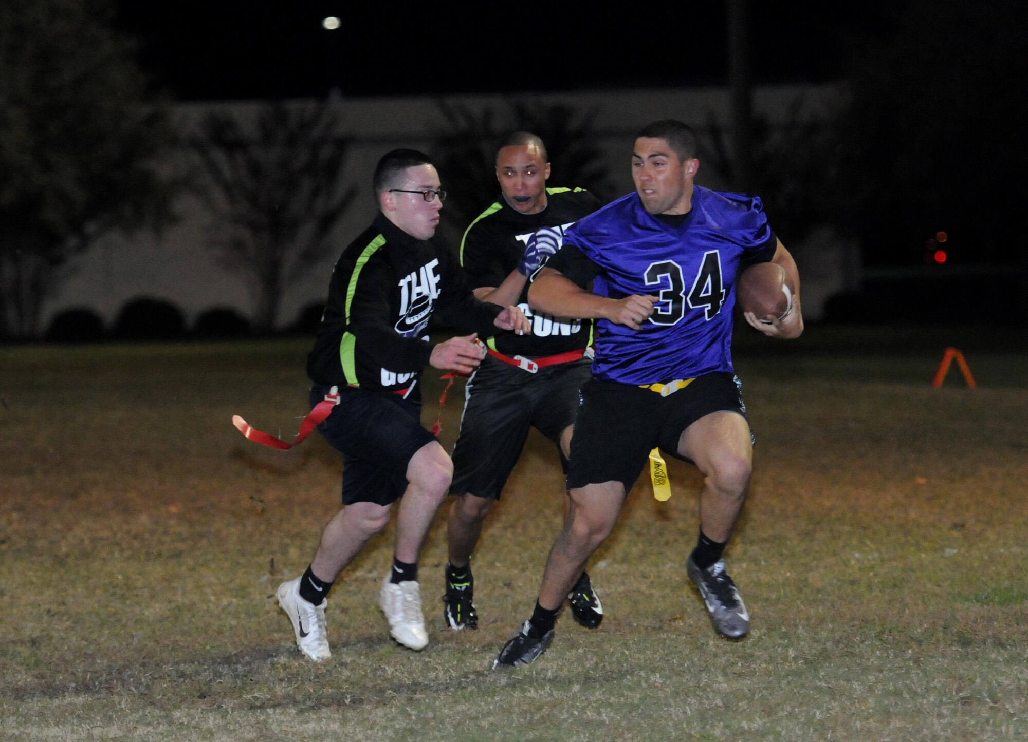 Petty Officer 2nd Class Gabriel Carvajal, Naval Mobile Construction Battalion 133rd  steelworker, and Petty Officer 3rd Class Durant Freeman, NMCB 133rd construction mechanic, chase Stone Barefield, 403rd Aircraft Maintenance Squadron crew chief, as he runs the ball during the intramural flag football championship game Nov. 23, 2015, Keesler Air Force Base, Miss. The 403rd Wing defeated NMCB, 30-18. (U.S. Air Force photo by Kemberly Groue)