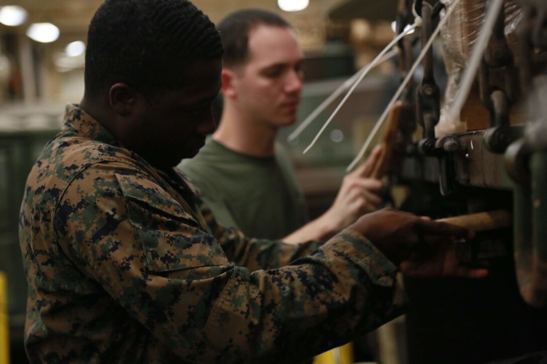 PHILIPPINE SEA (Nov. 23, 2015) U.S. Marine Cpl. Jeff Louis, front, scrubs the rust off a MK23 Medium Tactical Vehicle Replacement during preventive maintenance aboard the USS Anchorage (LPD 23). Louis is a motor transport operator with Combat Logistics Battalion 15, 15th Marine Expeditionary Unit. The 15th MEU is currently deployed in the Indo-Asia-Pacific region to promote regional stability and security in the U.S. 7th Fleet area of operations. (U.S. Marine Corps photo by Sgt. Steve H. Lopez/Released)