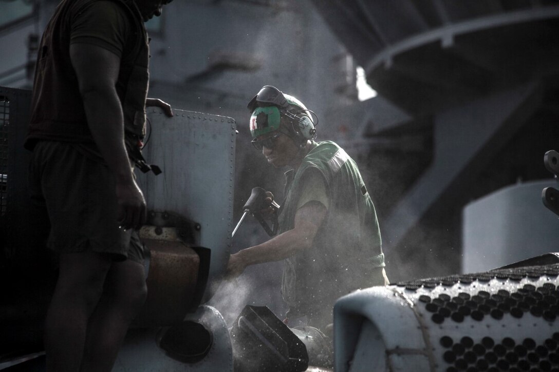U.S. Marines with Marine Medium Tiltrotor Squadron 161 (Reinforced), 15th Marine Expeditionary Unit, sprays an aircraft on the flight deck of the USS Essex, Nov. 23, 2015 on the Pacific Ocean. The 15th MEU is currently deployed in the Indo-Asia-Pacific region to promote regional stability and security in the U.S. 7th Fleet area of operations. 