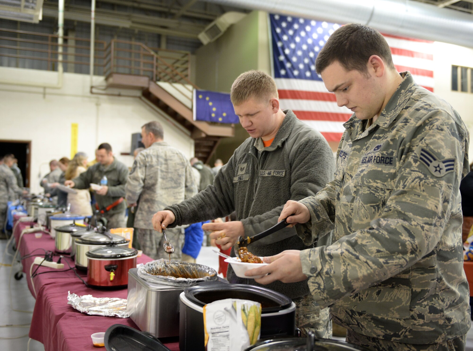 U.S. Air Force Senior Airman Greg Phelps, a 354th Maintenance Squadron (MXS) aerospace propulsion journeyman, and Staff Sgt. Mike Jones, a 354th MXS electrical environmental craftsman, scoop chili into their bowls during a maintenance group chili cook off at Eielson Air Force Base, Alaska, Nov. 20, 2015. The cook off gave Airmen a chance to showcase their skills and potentially earn bragging rights for the best dish. (U.S. Air Force photo by Senior Airman Racheal E. Watson/Released) 