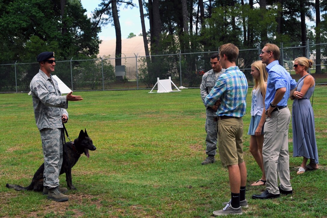 Senior Airman Austin Craven, 4th Security Forces Squadron military working dog handler, briefs descendants of U.S. Navy Lt. Seymour Johnson during a base tour, July 15, 2015, at Seymour Johnson Air Force Base, North Carolina. Craven explained duties and daily operations of MWD handlers and their canines. (U.S. Air Force photo/ Airman 1st Class Ashley Williamson)