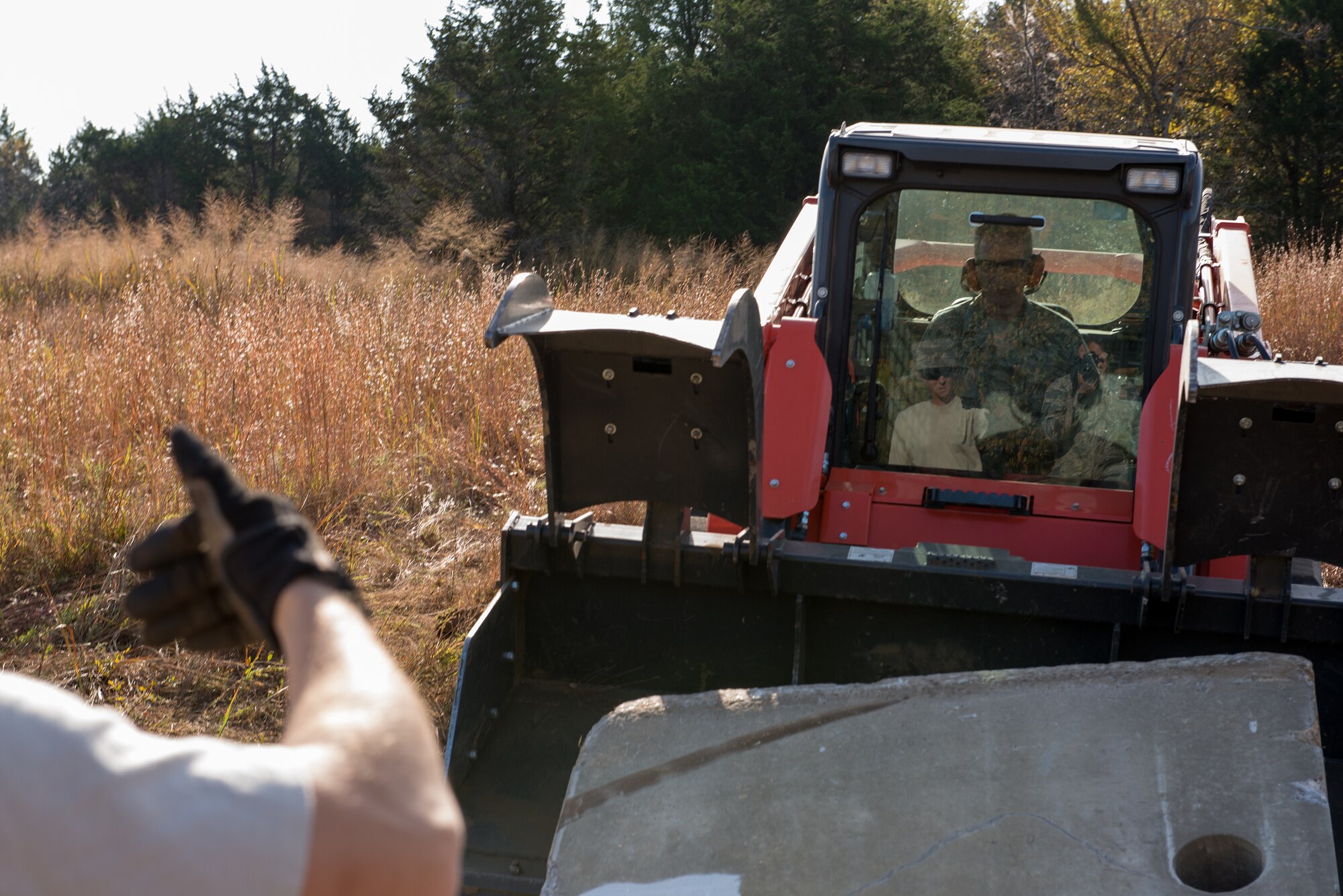 Airmen from the civil engineering squadrons of the 137th Air Refueling Wing, Oklahoma City, and the 138th Fighter Wing, Tulsa, Okla., communicate with hand signals during a debris clearance training at Camp Gruber, Oct. 19-23, 2015. The team-oriented training provided Airmen with the opportunity to work side-by-side with personnel from their sister wing.