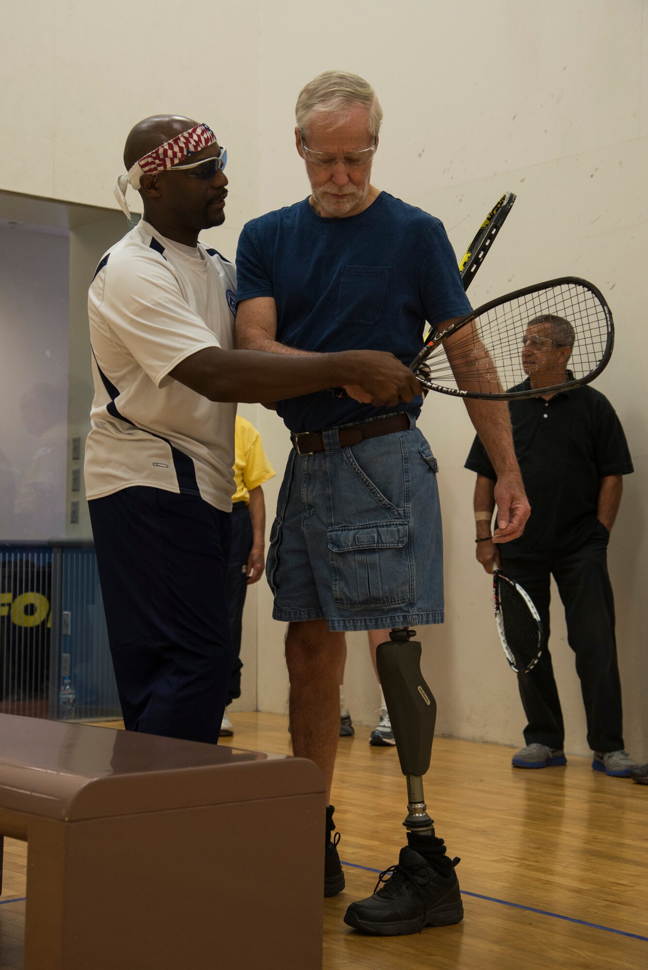 Steven Harper, the executive director of the Military Racquetball Federation, helps a veteran with technique and form November 13, 2015, at the James Sports Center. This is the first time a racquetball clinic for veterans and wounded warriors has been held at Scott Air Force Base. (U.S. Air Force photo by Airman Gwendalyn Smith)
