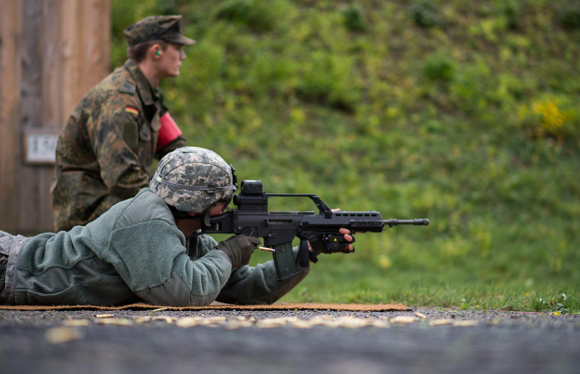 German Army Private 1st Class Dominik Lagershausen, Airborne Infantry Regiment 26, 4th Company Airborne Troop, watches U.S. Air Force Senior Airman Jonathan Ebner, 86th Security Forces Squadron unit fitness program manager, as he fires a G36 assault rifle Nov. 18, 2015, at Zweibruecken, Germany. More than 20 members of the 86th SFS shot German weapons to earn the Bundeswehr (German army) marksmanship badge and build the partnership between the two nations. (U.S. Air Force photo/Senior Airman Damon Kasberg)