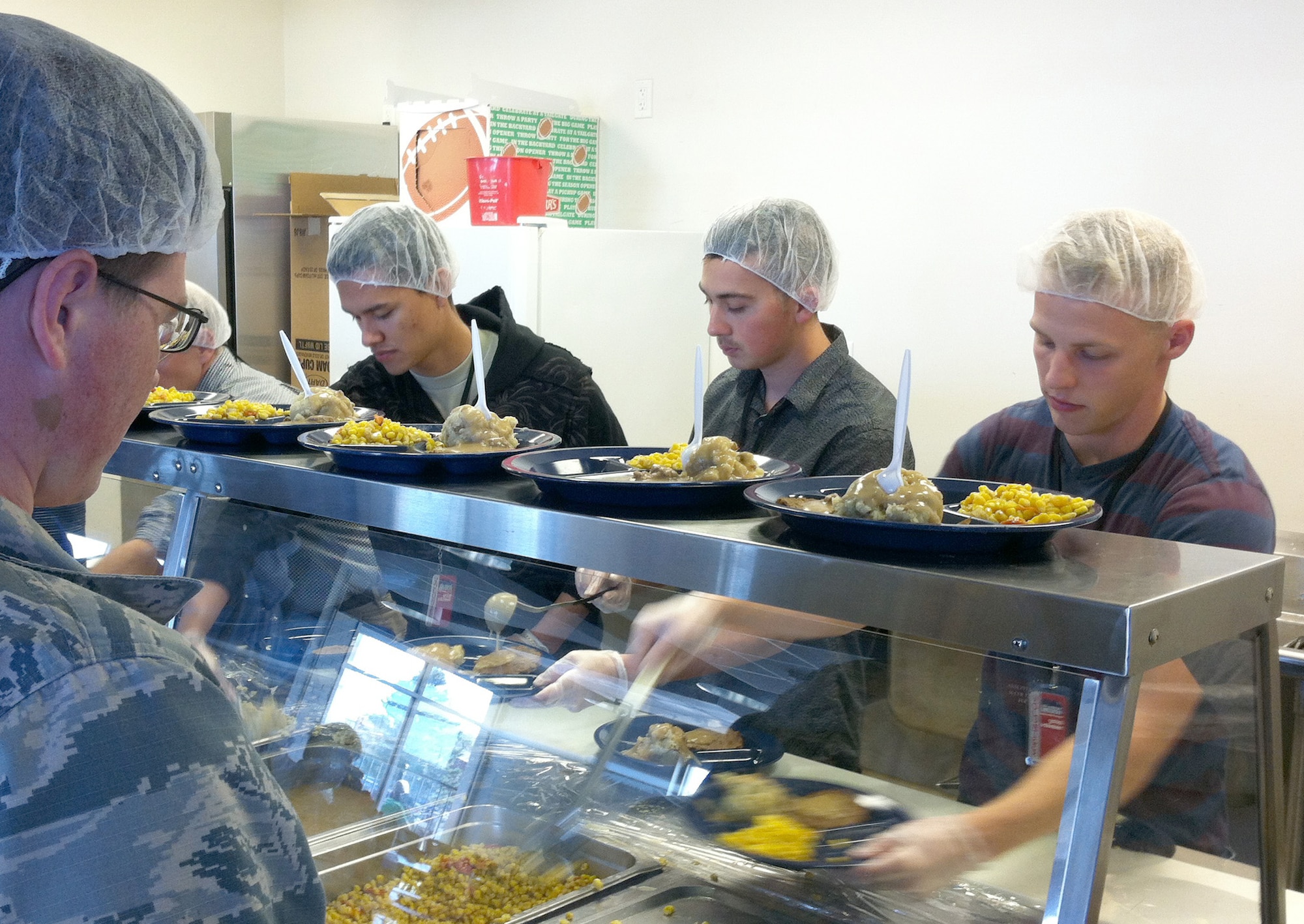 Members of the 72nd Operations Support Squadron prepare plates Nov. 12 at the City Rescue Mission in downtown Oklahoma City. Senior Airman Andrew Otts is in the foreground. From left are Airman 1st Class Enzo Ocsas, Senior Airman Robert Shifflett and Airman 1st Class Parker Reid.  (Courtesy photo/Released)