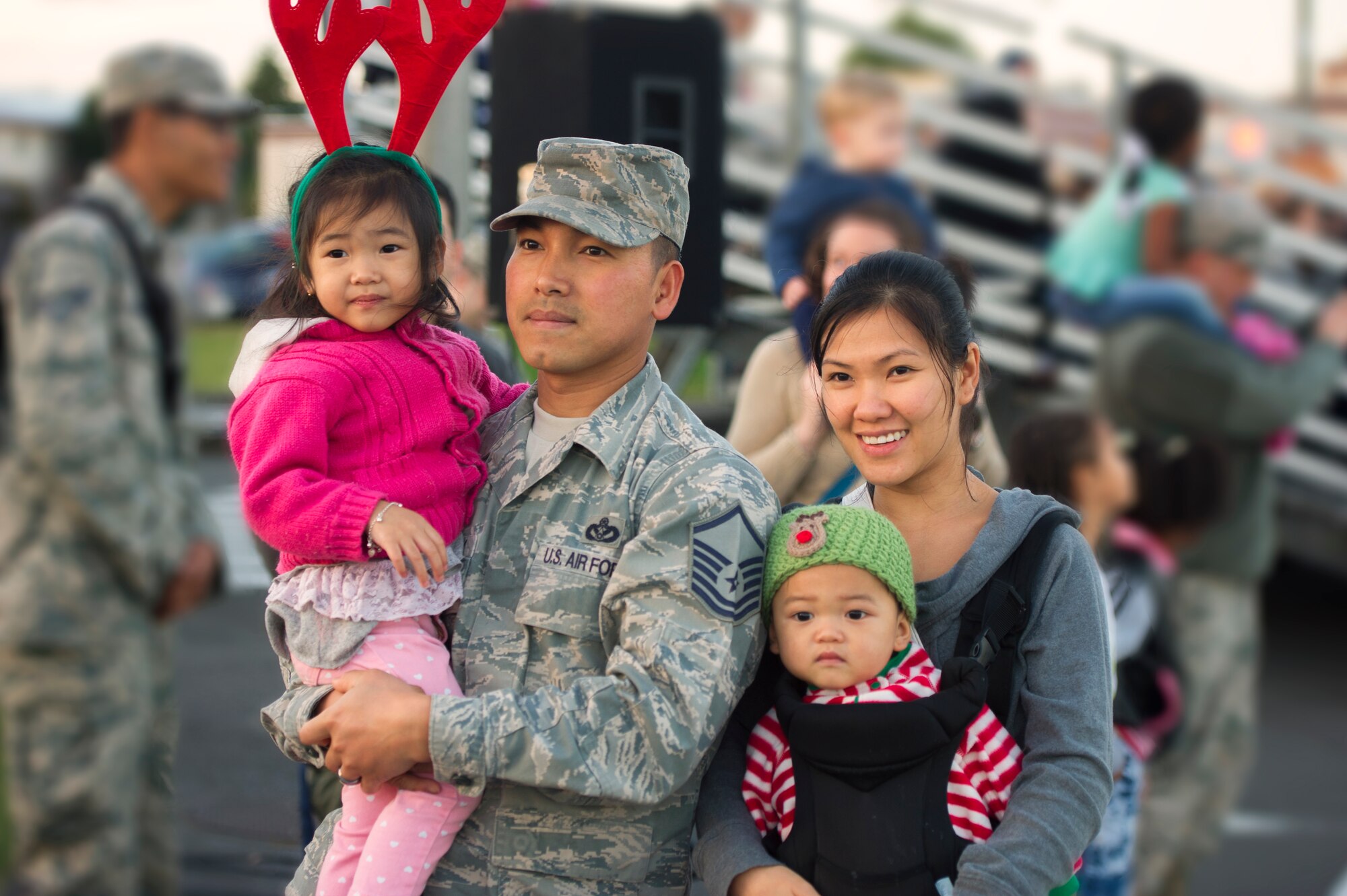 A family watches as Yokota Holiday Spectacular Parade participants march down Airlift Ave. at Yokota Air Base, Japan, Nov. 24, 2015. The parade consisted of bands from different military branches, the Yokota Car Club, the Scary Blossoms roller derby team and many more. (U.S. Air Force phot by Airman 1st Class Delano Scott/Released)