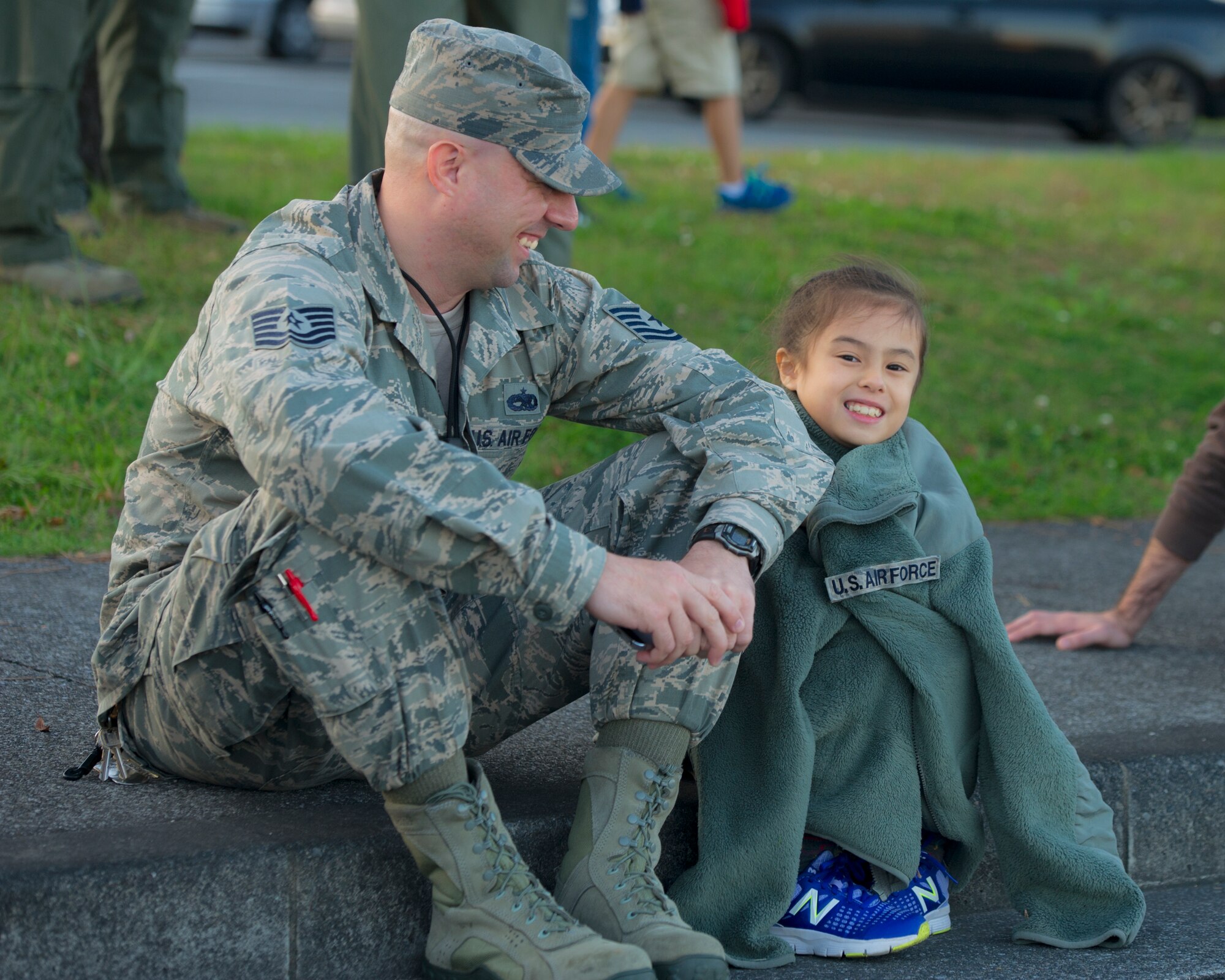 A father and daughter watch the Yokota Holiday Spectacular Parade at Yokota Air Base, Japan, Nov. 24, 2015. The parade consisted of bands from different military branches, the Yokota Car Club, the Scary Blossoms roller derby team and many more. (U.S. Air Force phot by Airman 1st Class Delano Scott/Released)