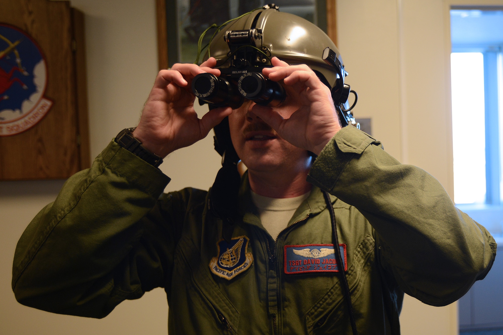 Tech. Sgt. David Jacobs, 459th Airlift Squadron NCO in charge of training, dons the Japan Ground Self-Defense Force night vision device with daytime-training filter lenses at Yokota Air Base, Japan, Nov. 16, 2015. JGSDF members from the Eastern Army Helicopter visited the 459 AS as part of a search and rescue capability exchange. (U.S. Air Force photo by Senior Airman David C. Danford/Released)