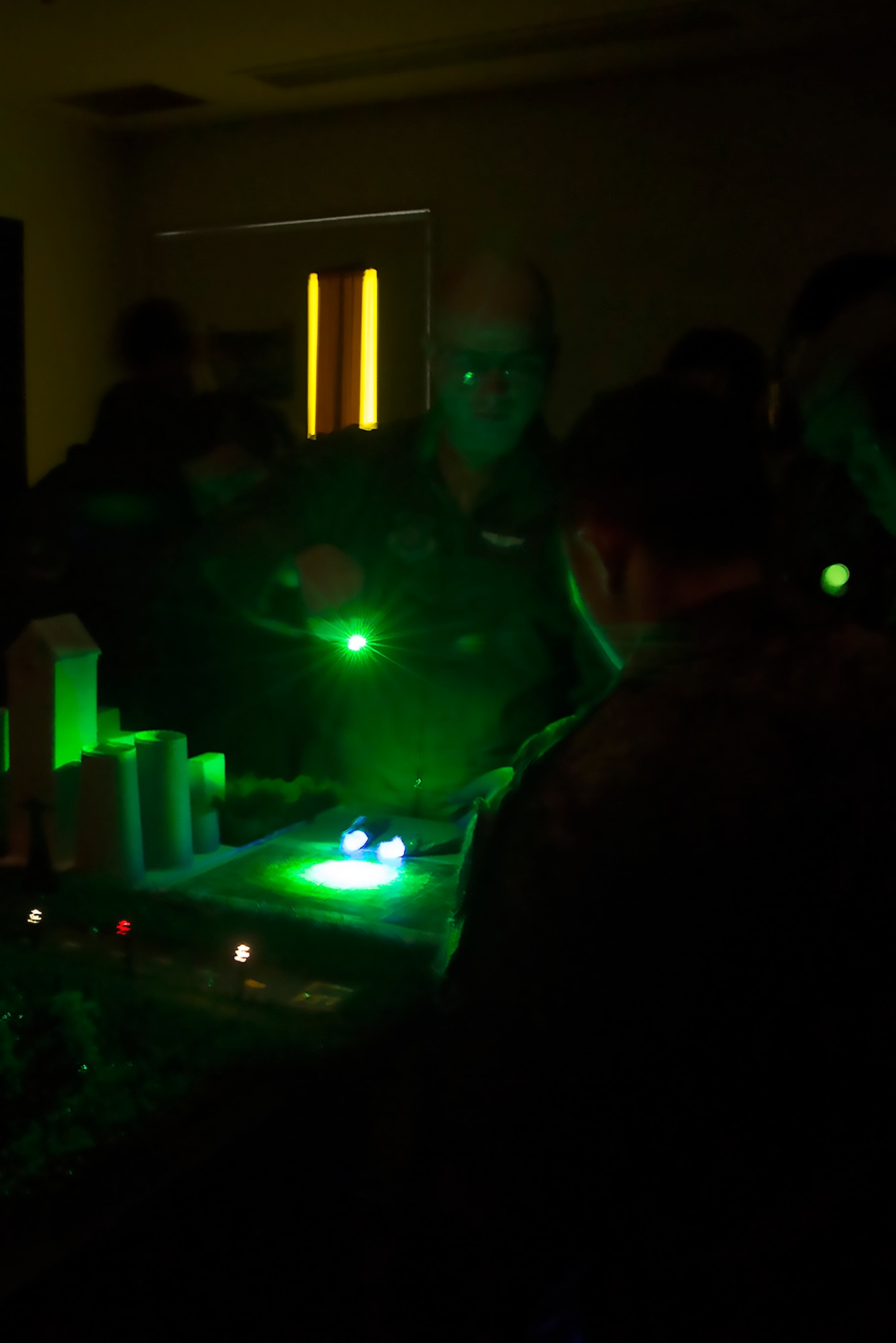 Tech. Sgt. Christopher Rector, 459th Airlift Squadron UH-1N Iroquois standards and evaluations NCO in charge, displays night vision search and rescue capabilities to a Japan Ground Self-Defense Force helicopter aircrew at Yokota Air Base, Japan, Nov. 16, 2015. Rector's diorama demonstrated some of the difficulties pilots face flying at night by simulating the lights of Tokyo as seen through night vision goggles. (U.S. Air Force photo by Senior Airman David C. Danford/Released)