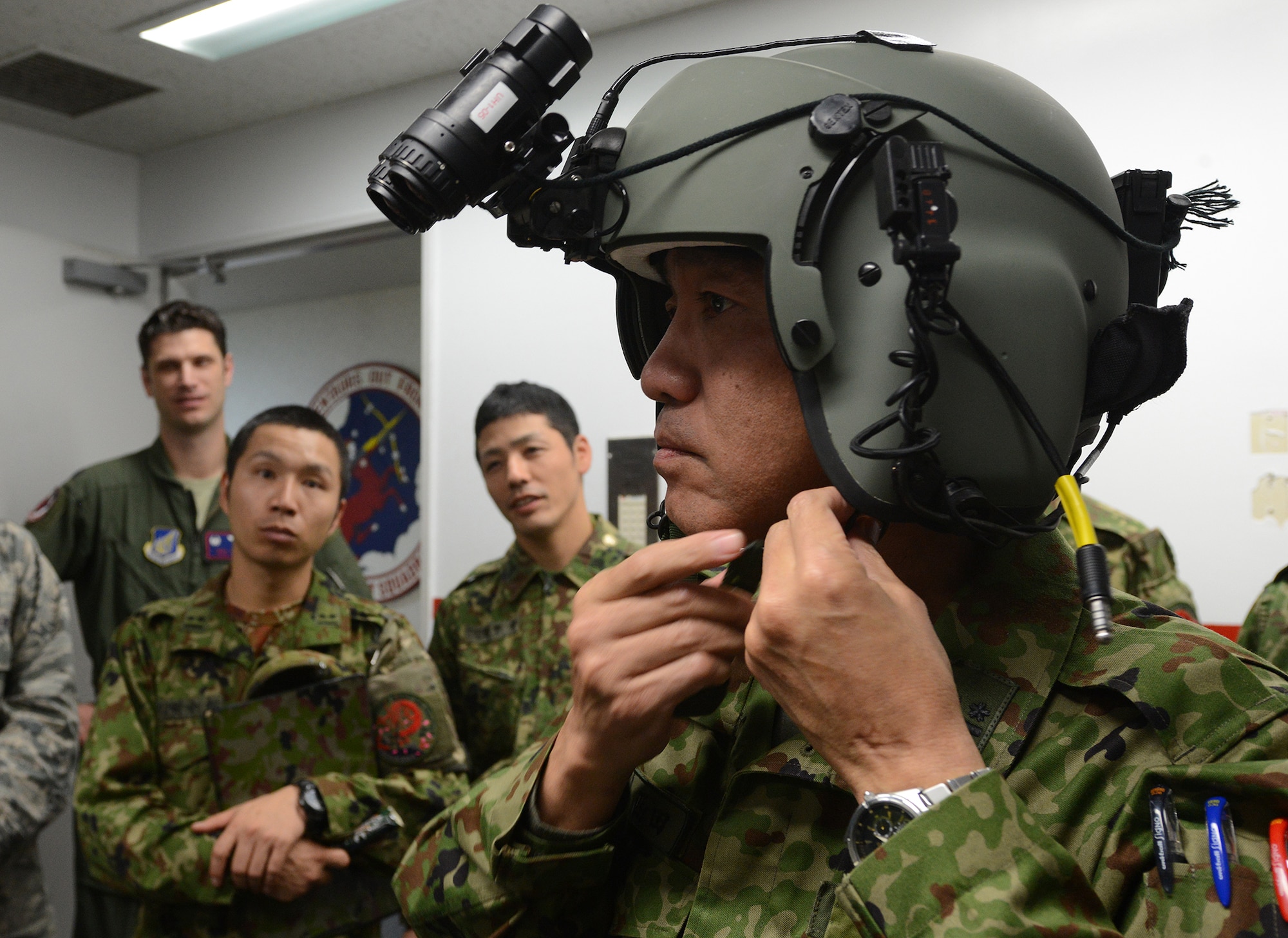 Lt. Col. Akihiko Nishida, Japan Ground Self-Defense Force Eastern Army Helicopter commander, dons a U.S. Air Force helmet with attached night vision goggles during a search and rescue capability exchange at Yokota Air Base, Japan, Nov. 16, 2015. The helmet is heavier than the Japanese equivalent holding more battery packs to counterbalance the weight of the goggles. (U.S. Air Force photo by Senior Airman David C. Danford/Released)