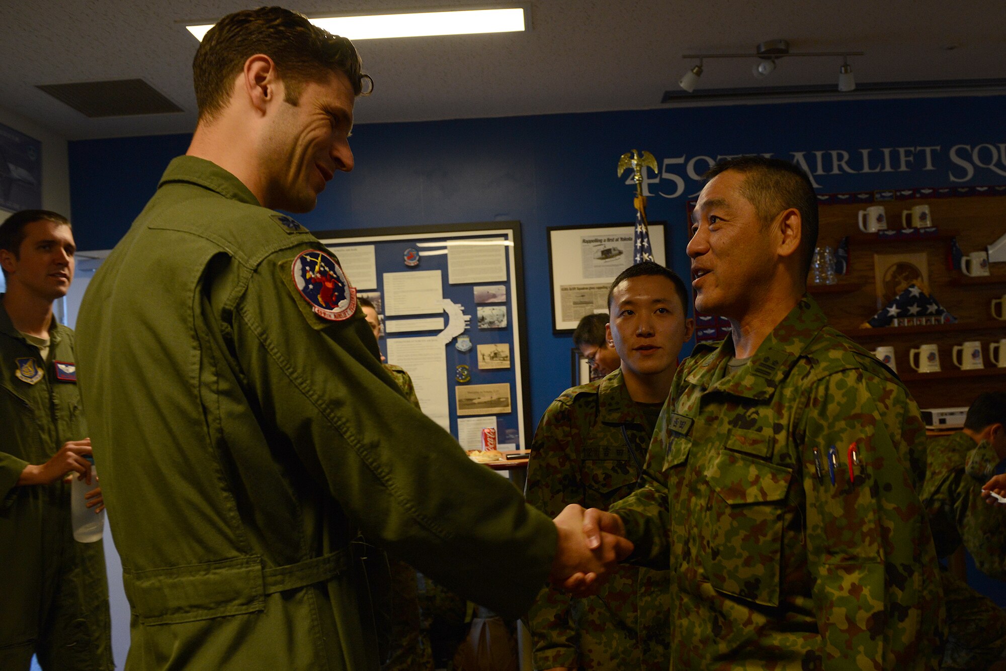 Lt. Col. William Martin, 459th Airlift Squadron commander, shakes hands with Lt. Col. Akihiko Nishida, Japan Ground Self-Defense Force Eastern Army Helicopter commander, during a search and rescue capability exchange at Yokota Air Base, Japan, Nov. 16, 2015. The exchange included briefings on Japanese and U.S. night vision capabilities, a static display of a UH-1N Iroquois with a hoist and a barbecue. (U.S. Air Force photo by Senior Airman David C. Danford/Released)