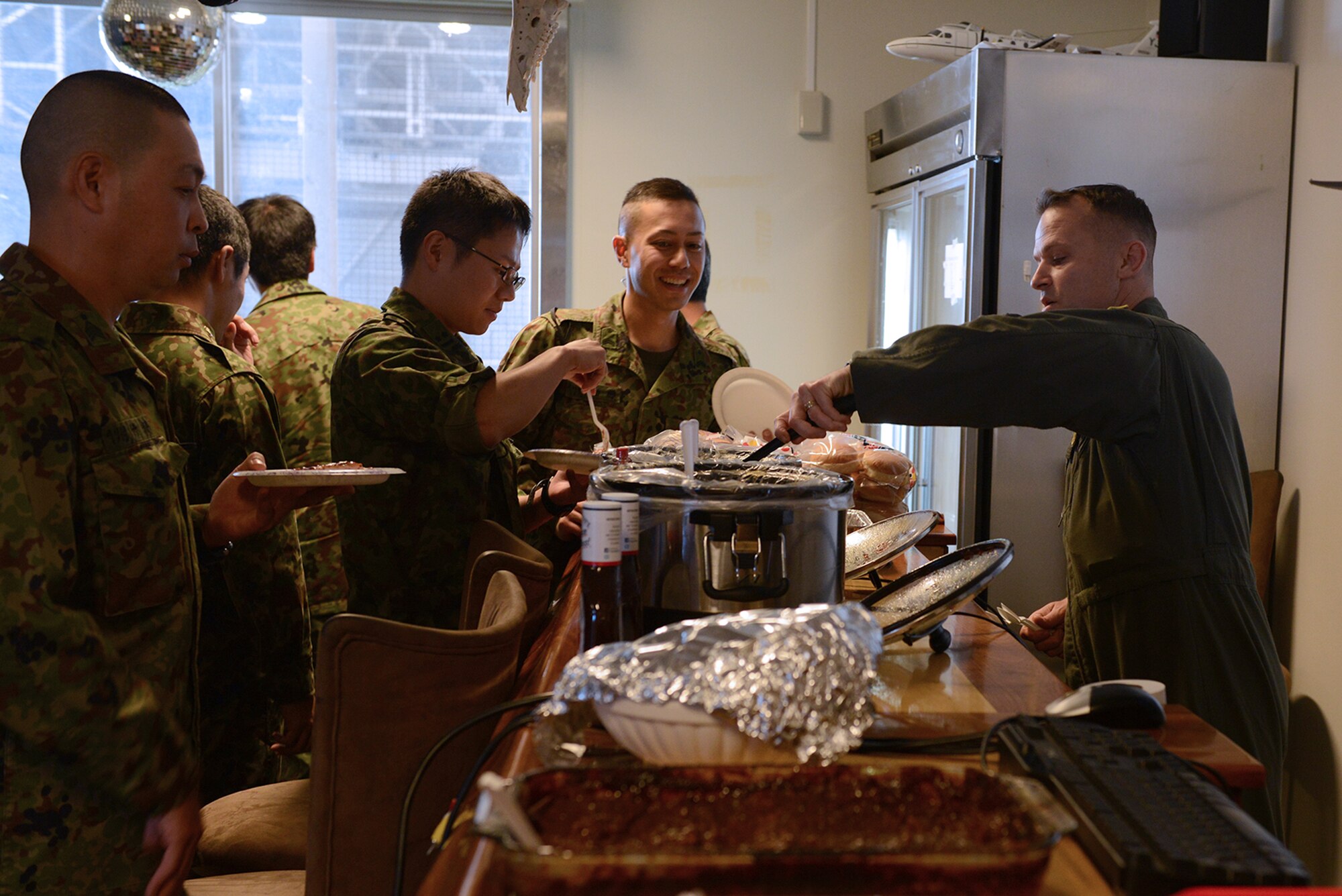 Senior Master Sgt. Edward Sponenburg, 36th Airlift Squadron C-130 Hercules flight engineer, serves food to members of the Japan Ground Self-Defense Force in the 459th Airlift Squadron heritage room at Yokota Air Base, Japan, Nov. 16, 2015. JGSDF members from the Eastern Army Helicopter visited the 459 AS as part of a search and rescue capability exchange. (U.S. Air Force photo by Senior Airman David C. Danford/Released)