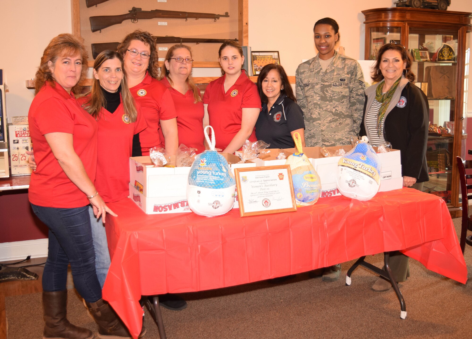 American Legion Post 10 Auxiliary members and Horsham Air Guard Station’s Airman and Family Readiness office representatives surround a table of abundant Thanksgiving meal donations to the 111th Attack Wing in Fort Washington, Pennsylvania on Nov. 21, 2015. Janis Navo, Auxiliary president (left) will be kicking off  the post’s Christmas drive to fulfill wish lists for the USO. (U.S. Air National Guard photo by Master Sgt. Christopher Botzum/Released)   