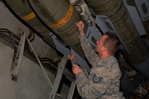 An airman deployed to Al Udeid Air Base, Qatar writes a message on a bomb inside a B-1 Lancer bomb bay during a tour of the aircraft at AUAB Nov. 24. Forty service members took part in the tour which featured a presentation of the B-1's capabilities and videos showcasing strikes the bomber has carried out. (U.S. Air Force photo by Tech. Sgt. James Hodgman/Released)