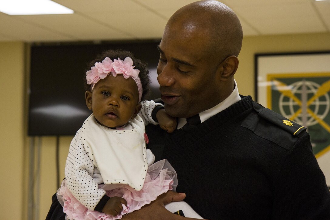Maj. Micah Ramseur, a logistics officer with the 200th Military Police Command, shares a moment with his 7-month-old daughter, Michyla, during his promotion ceremony Nov. 24, at a U.S. Army Reserve center at Fort Meade, Md. Of Baltimore, Ramseur stressed the importance of family and the roles they play in a Soldier's career during his promotion speech. (U.S. Army photo by Sgt. Marc Loi)