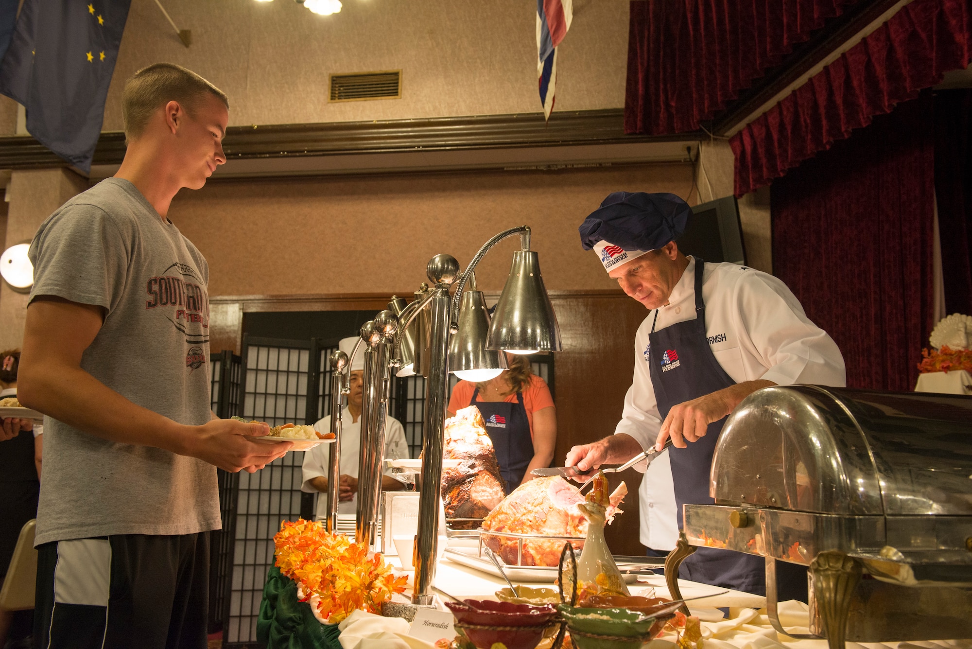 Brig. Gen. Barry Cornish, 18th Wing commander, serves Airman 1st Class Devin Ehret, 18th Equipment Maintenance Squadron mechanic, a slice of ham during Thanksgiving Nov. 26, 2015, at Kadena Air Base, Japan. Kadena's leadership served various Thanksgiving dishes to more than 100 Airmen and their families during the holiday. (U.S. Air Force photo by Senior Airman Omari Bernard)